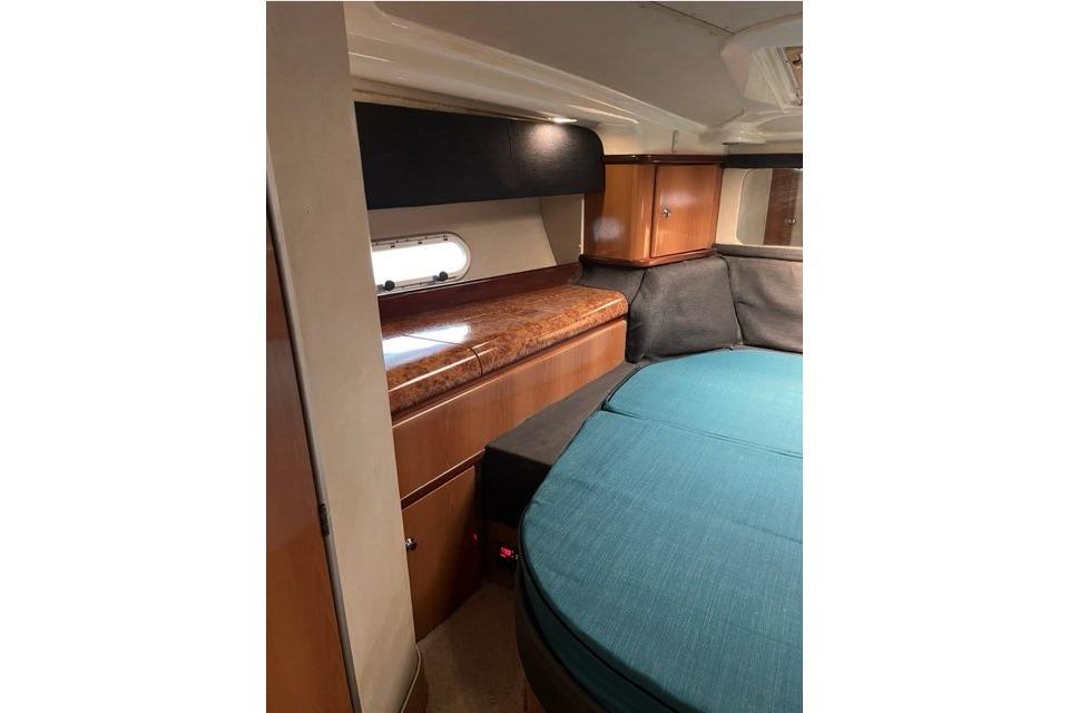 Interior of 1999 Sealine F44 yacht with wood cabinetry and teal upholstery.