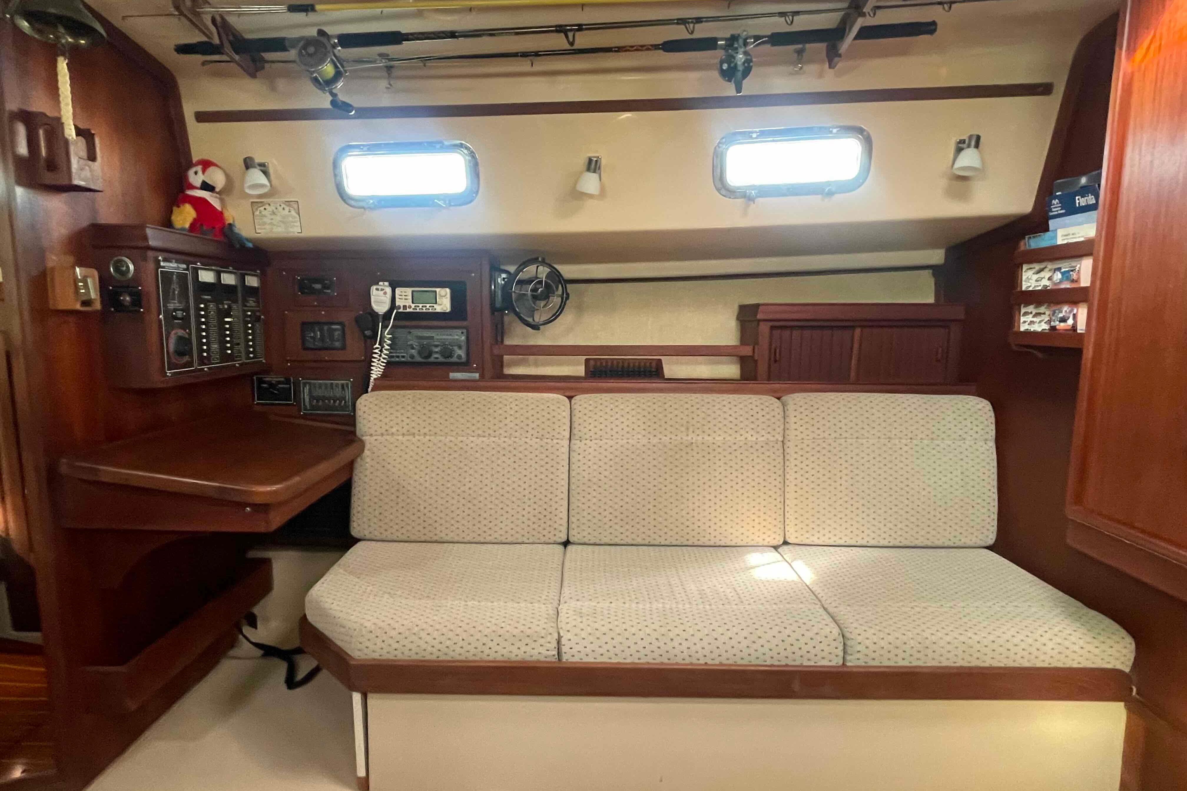 Interior of 1989 Island Packet 35 sailboat with navigation station and cushioned seating.