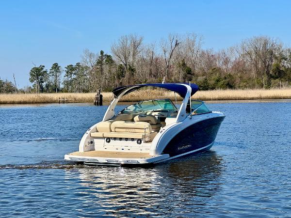 2018 Regal 3300 on calm water with blue canopy and beige interior.