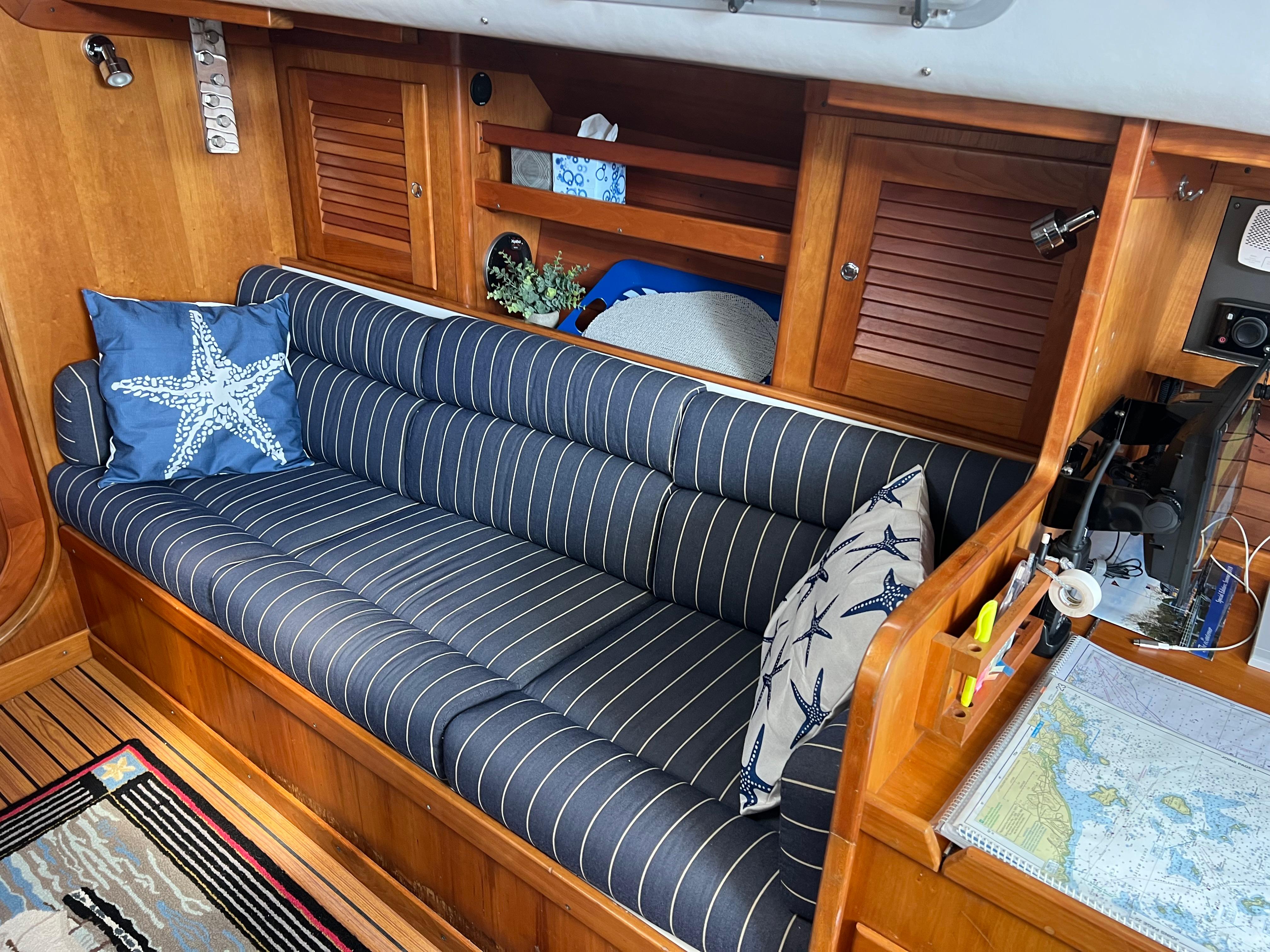 Cozy interior of 2001 J Boats J/120 with striped cushions and nautical decor.