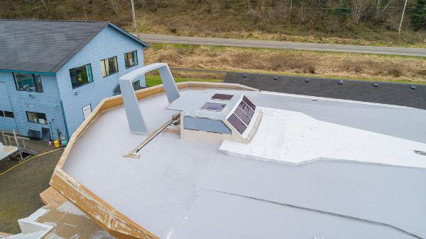 2025 Catamaran Bloomfield 86 Motorsailor under construction near a blue house.