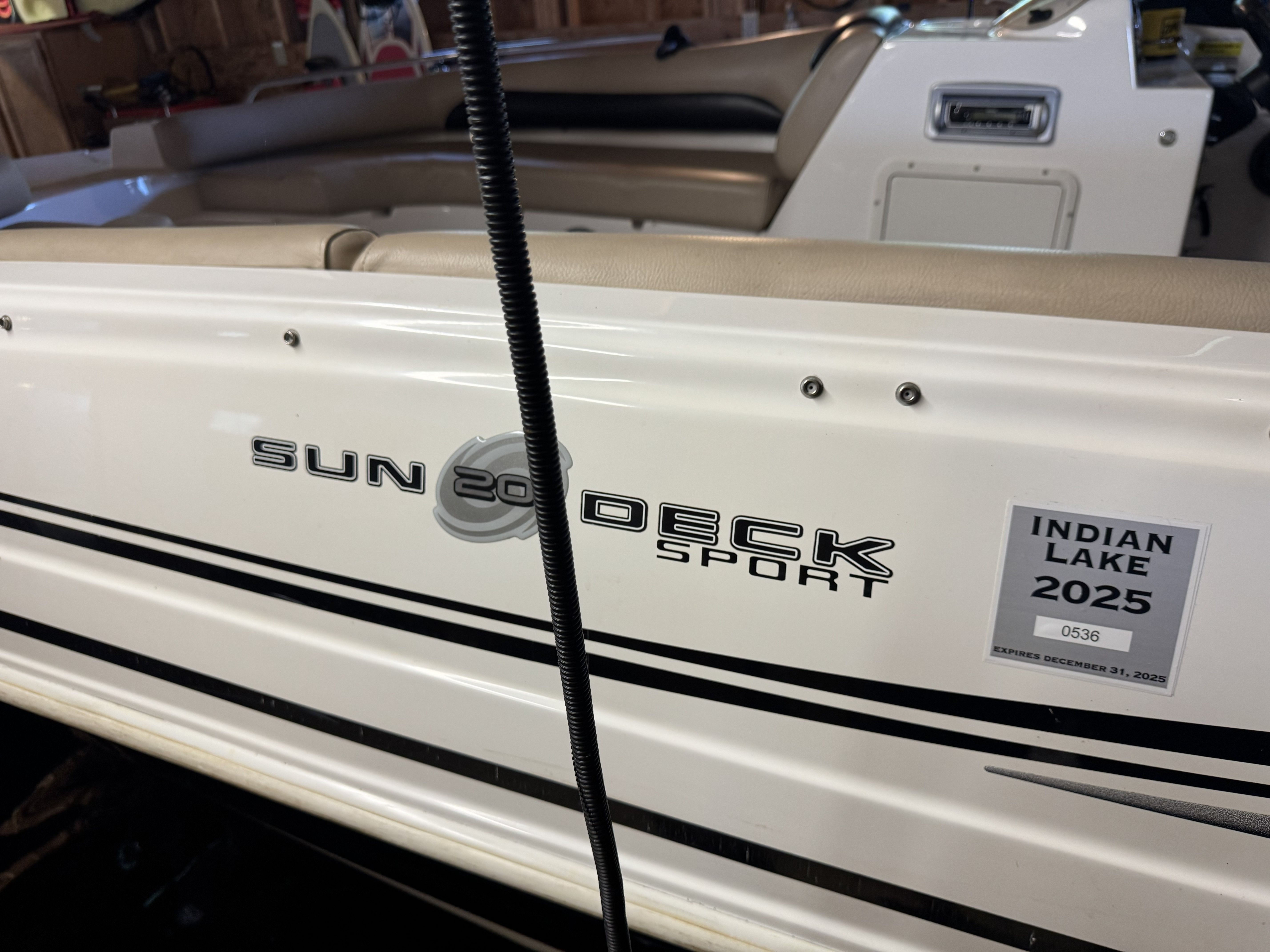 Close-up of a white boat with "Sun Deck Sport" lettering and "Indian Lake 2025" sticker.