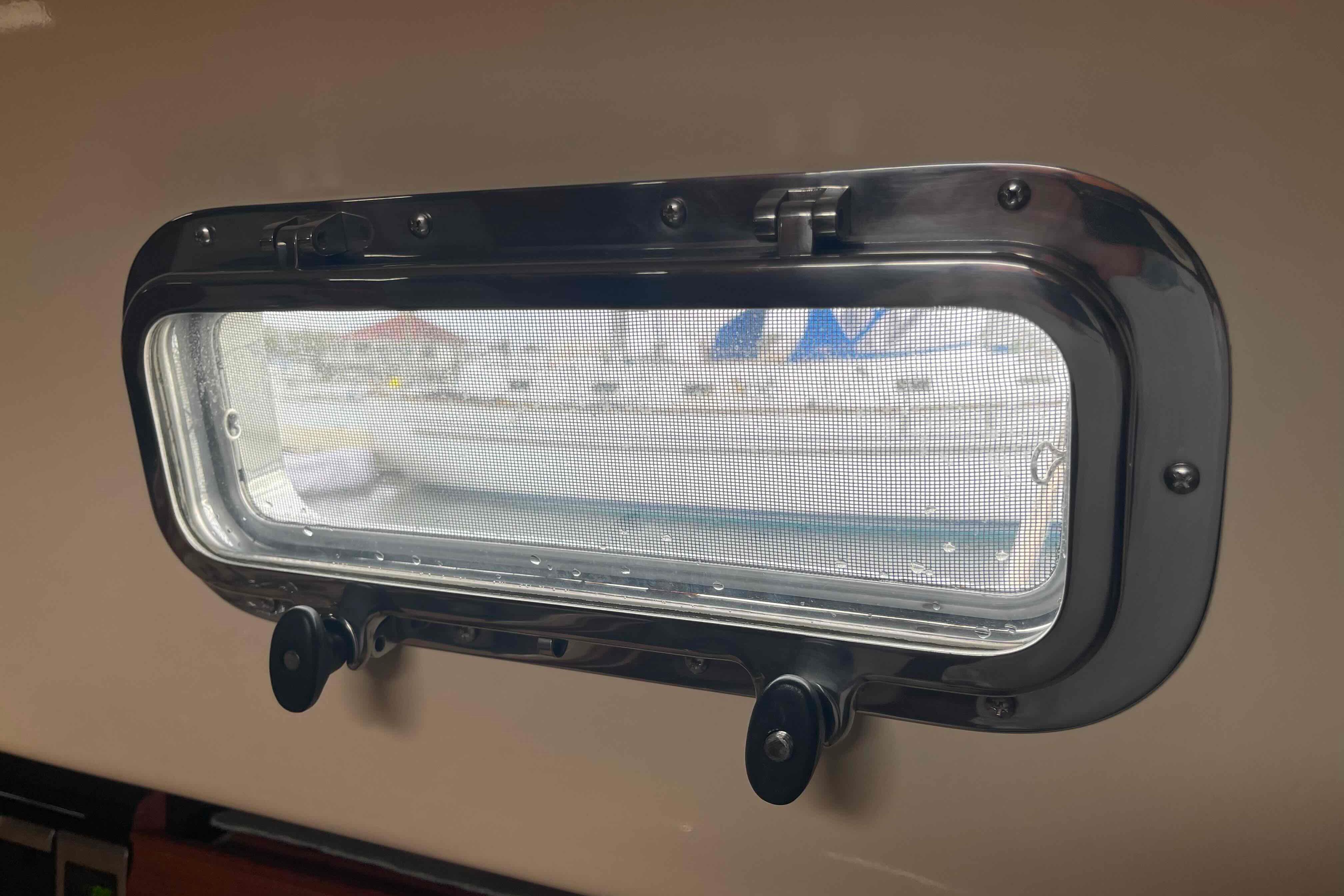 Porthole view from 1998 Island Packet 40 sailboat, showcasing marina and boats outside.