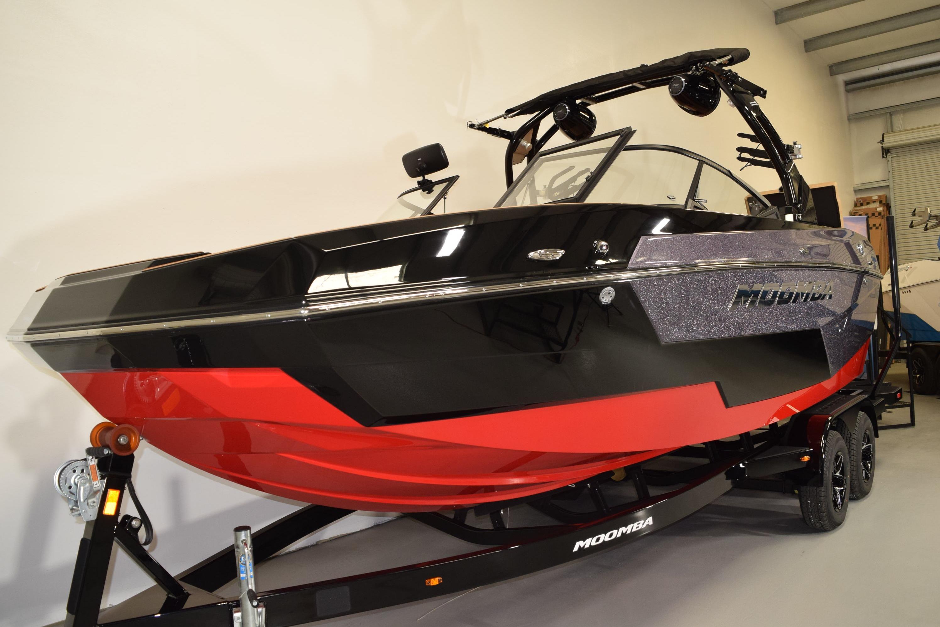 2026 Moomba Max boat in showroom, featuring sleek black and red design.
