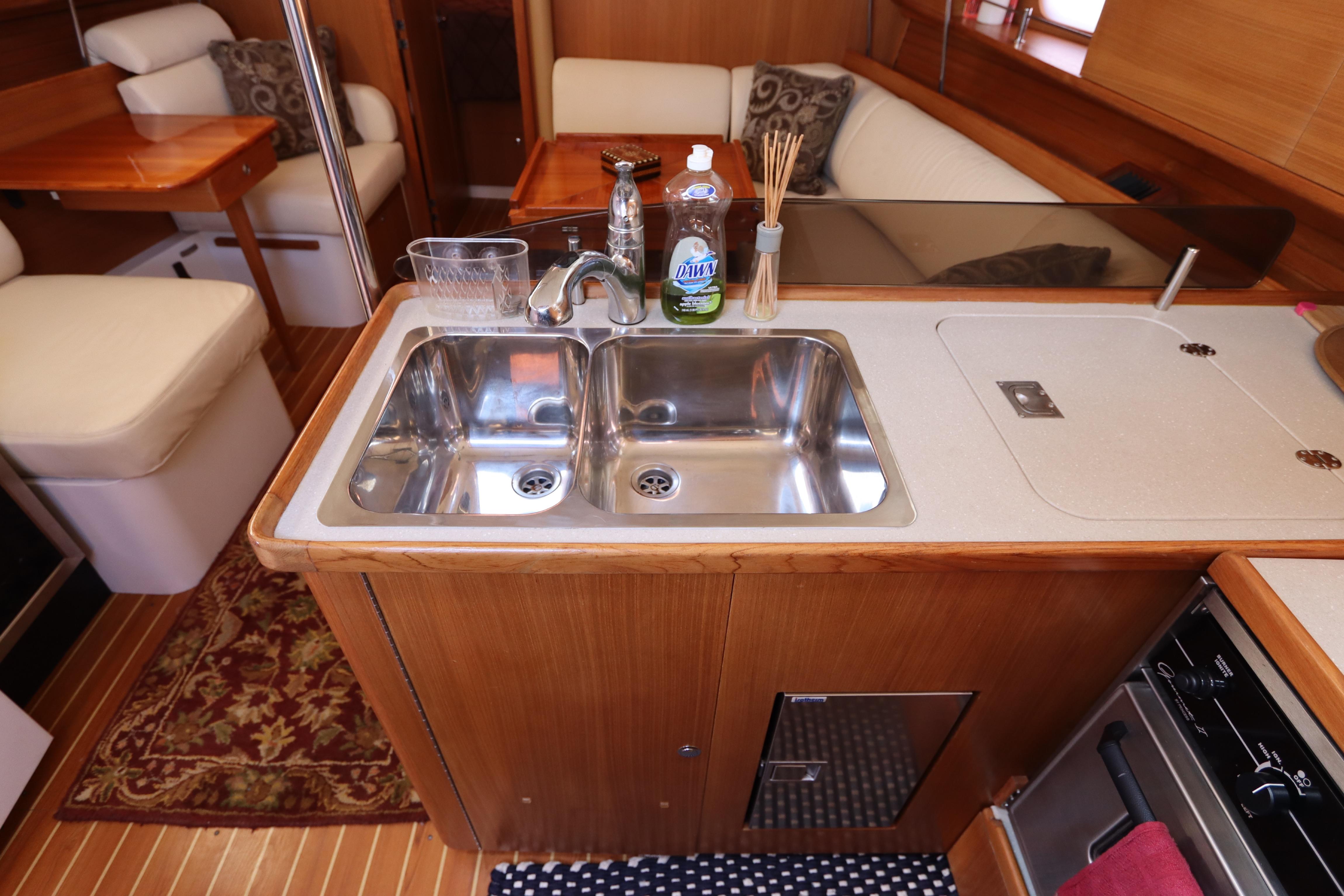 Interior of 2011 Catalina 355 yacht kitchen with double sink and wooden cabinetry.