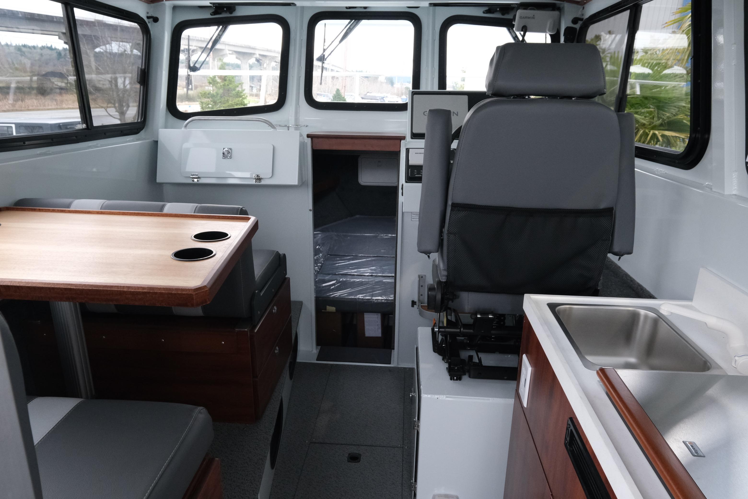 Interior of 2026 Hewescraft 270 Pacific Explorer, featuring seating, table, and kitchenette.