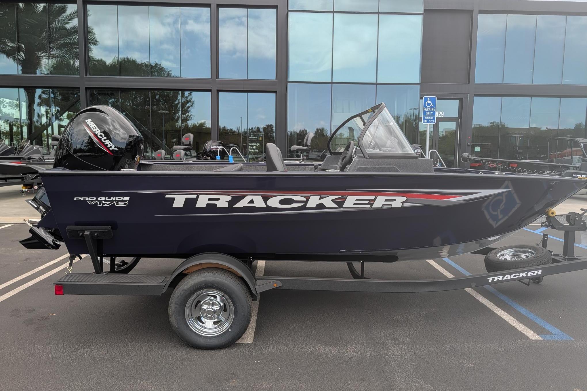 2026 Tracker Pro Guide V-175 WT boat on trailer, parked outside modern building.