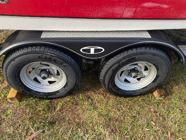 2022 Tahoe 2150 trailer wheels on grass, featuring dual tires and wooden blocks.