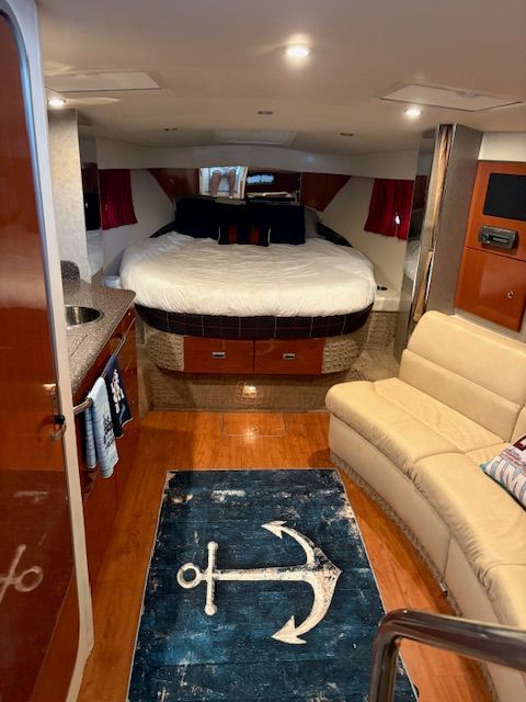 Interior of a 2007 Formula 34 Performance Cruiser with cozy bed, sofa, and anchor-themed rug.