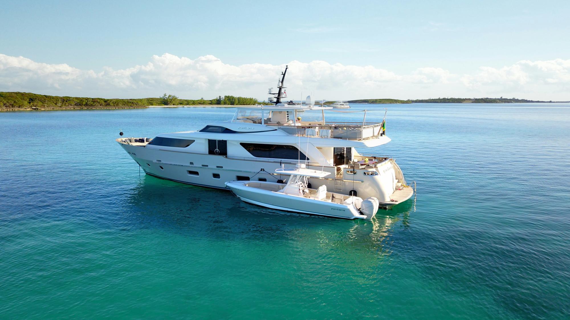 Sanlorenzo SD92 2012 yacht anchored in clear blue waters, with a small boat nearby.