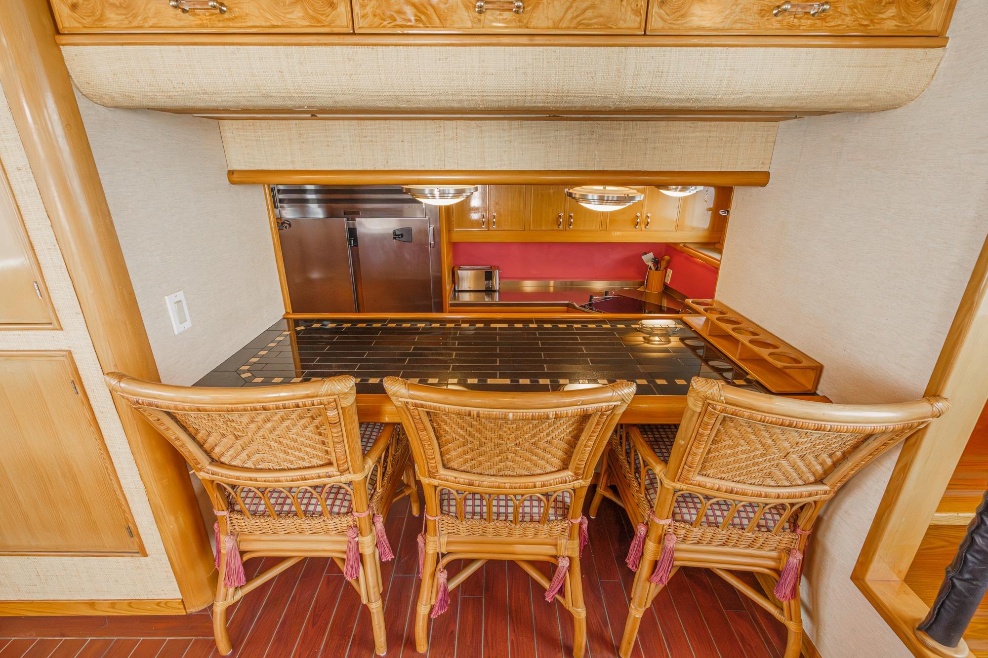 Luxurious 1990 Seaton Long Range Cruiser kitchen with wicker chairs and elegant wood cabinetry.