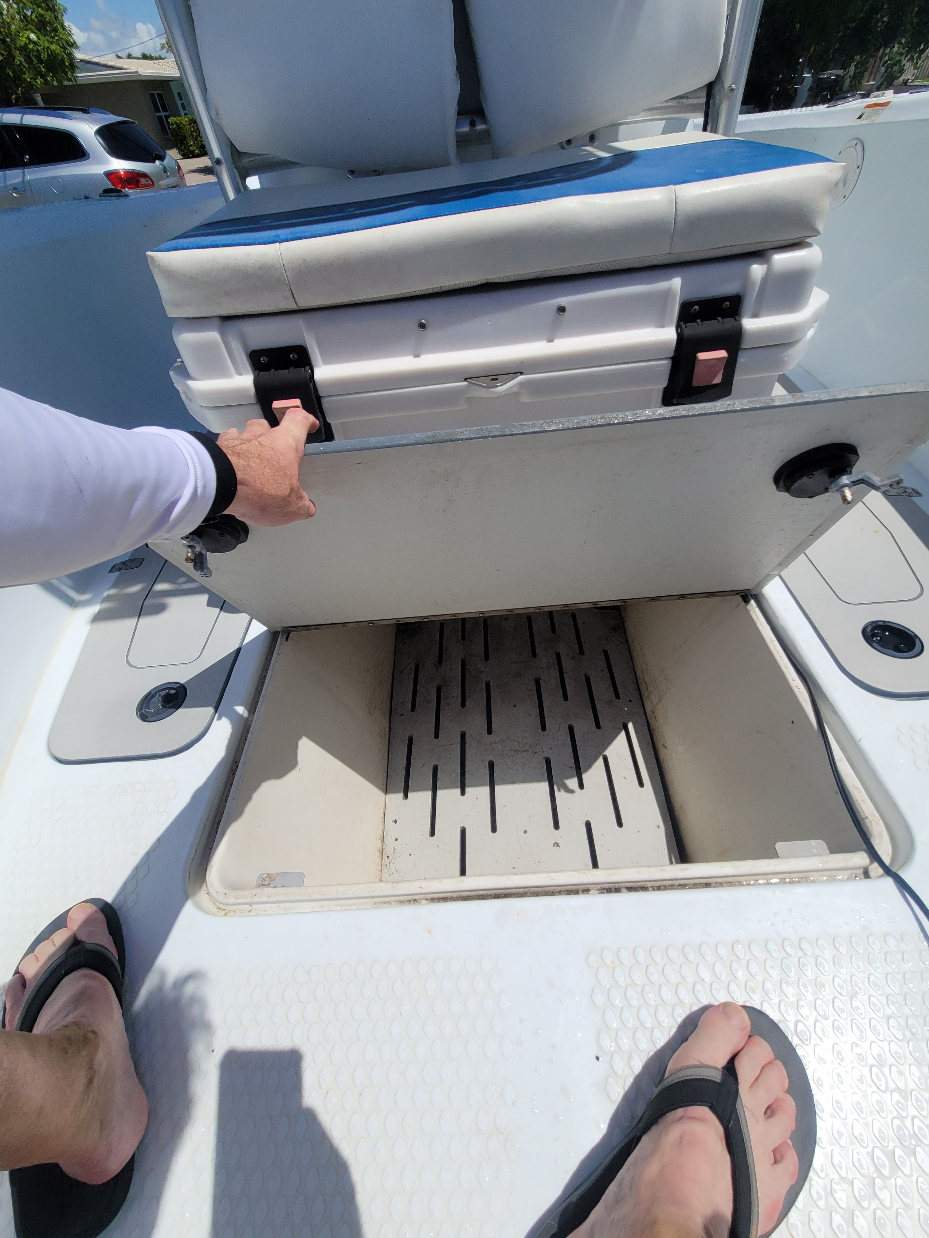A man opens a storage compartment hatch on a boat.