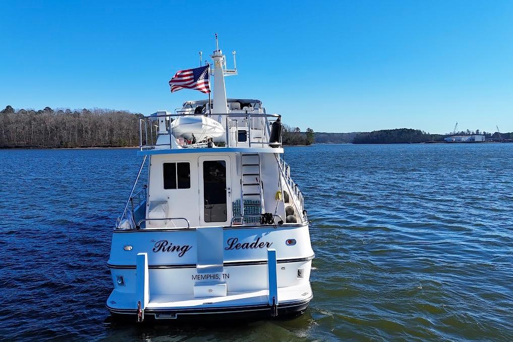 Nordic Tug 54, 2007 model, cruising on a serene lake under a clear blue sky.