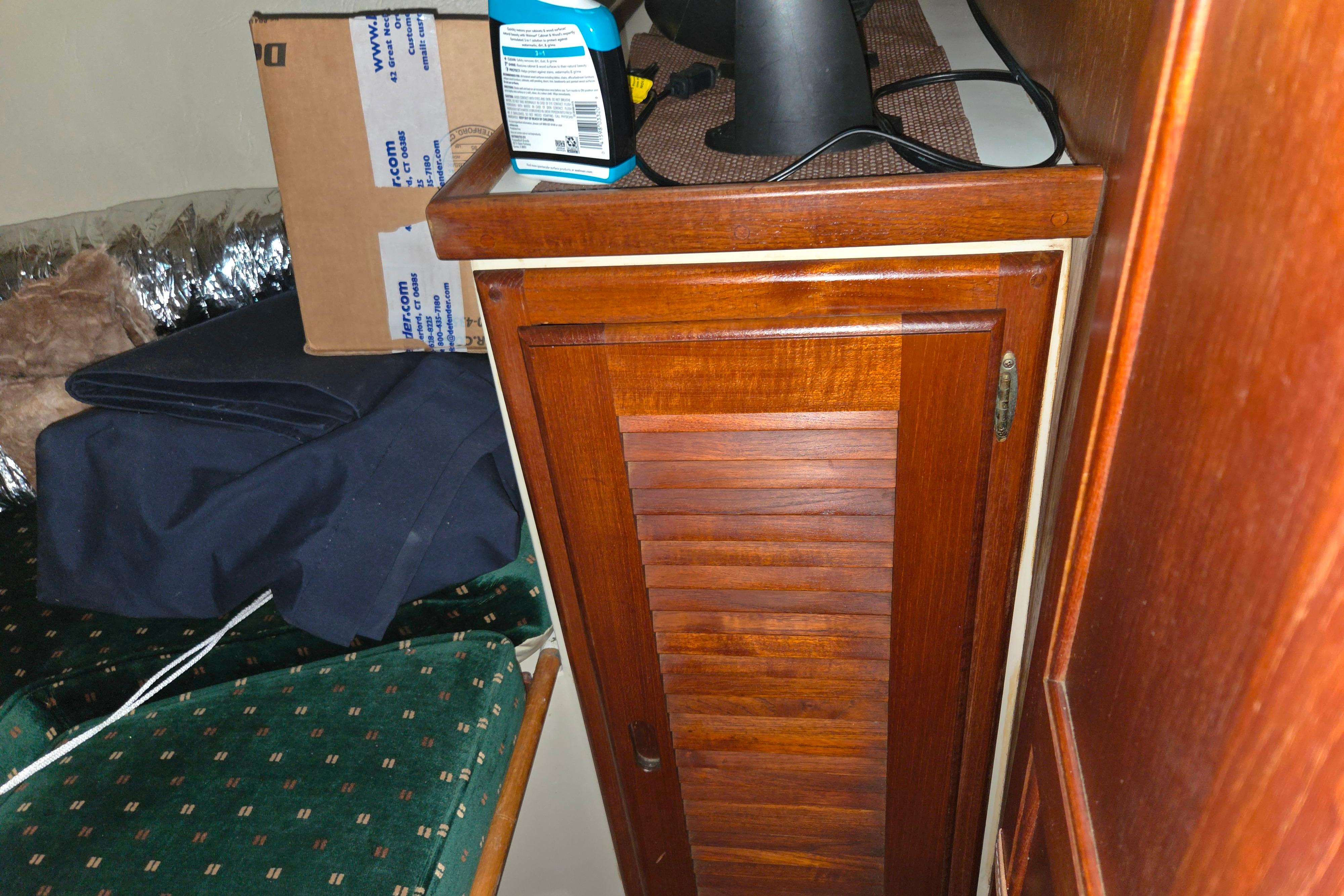 Wooden cabinet inside a 1986 Catalina 355 boat, surrounded by various items.