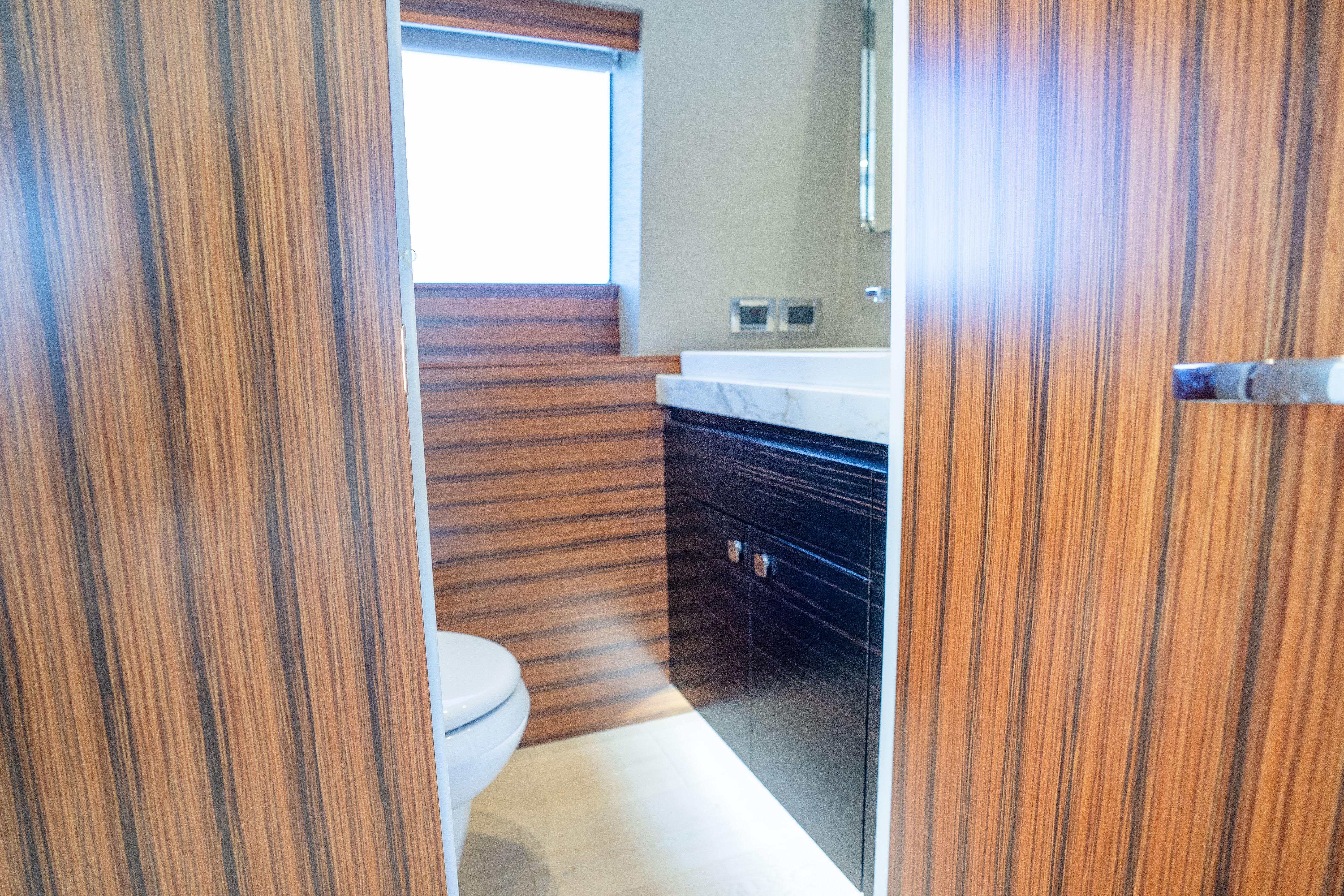 Luxurious bathroom interior of 2021 Hatteras M75 Panacera yacht with wood paneling.