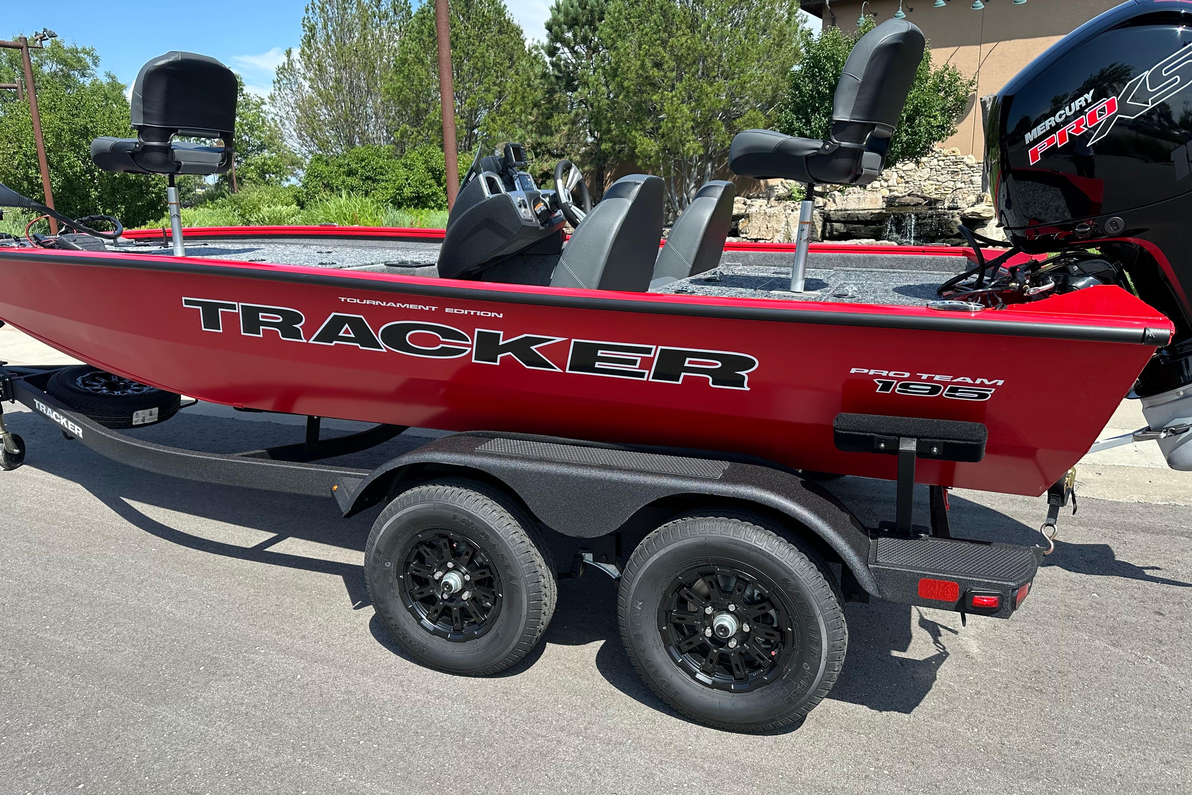 Red 2026 Tracker Pro Team 195 boat on trailer, featuring sleek design and comfortable seating.