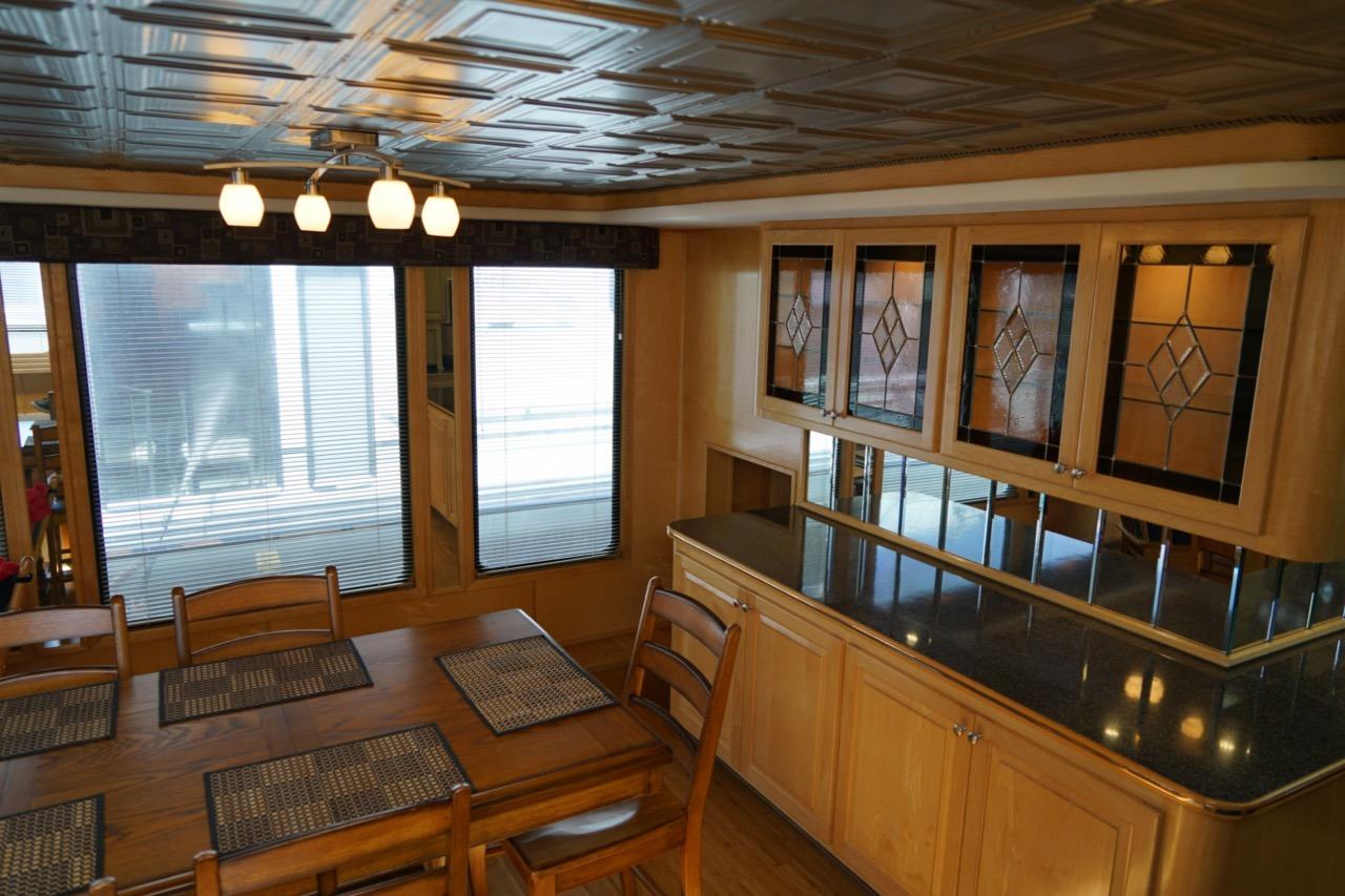 Dining area in 2000 Stardust Cruisers houseboat with wooden furniture and decorative glass cabinets.