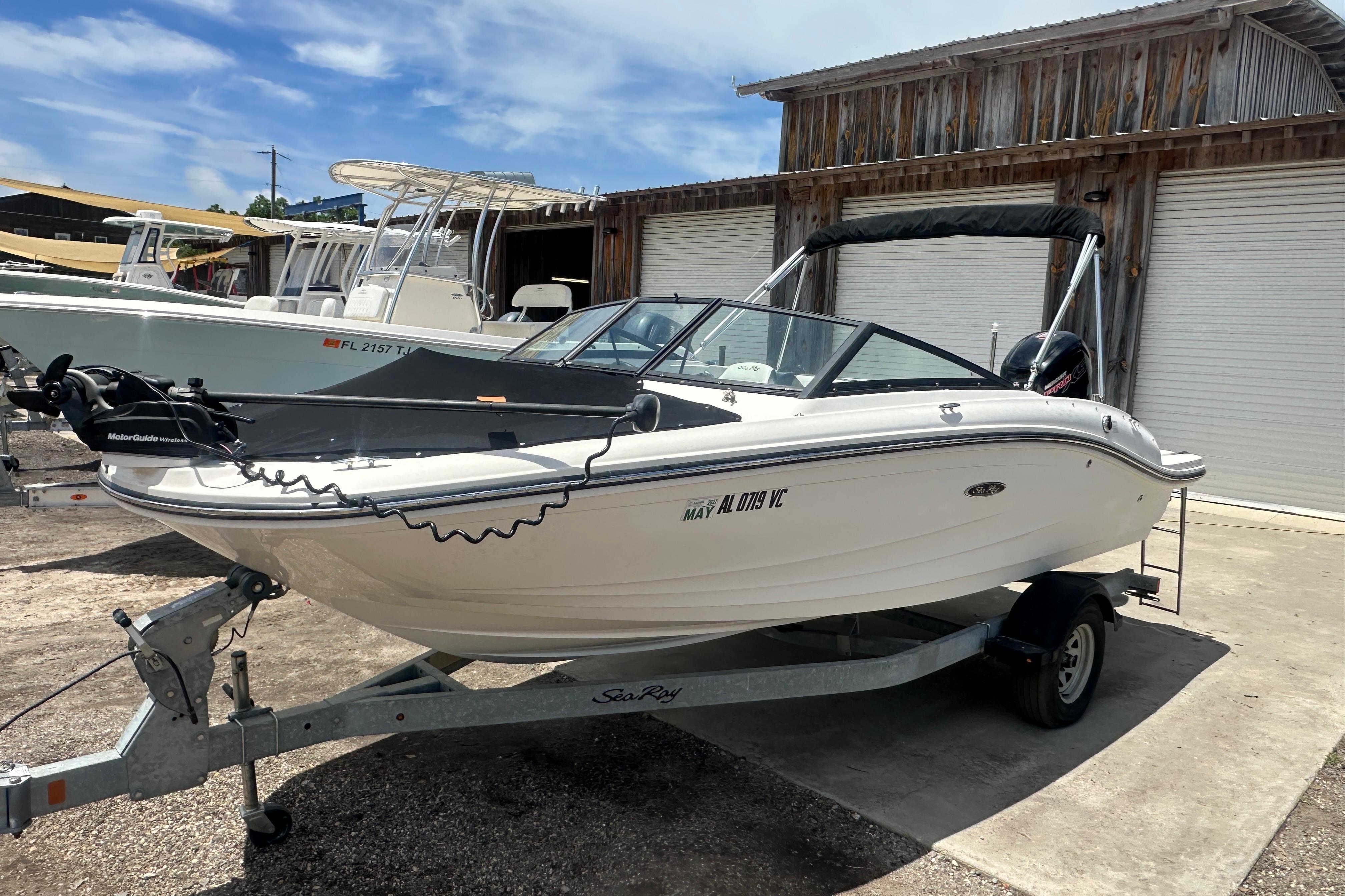 2017 Sea Ray SPX 190 Outboard boat on trailer, parked outdoors near wooden building.
