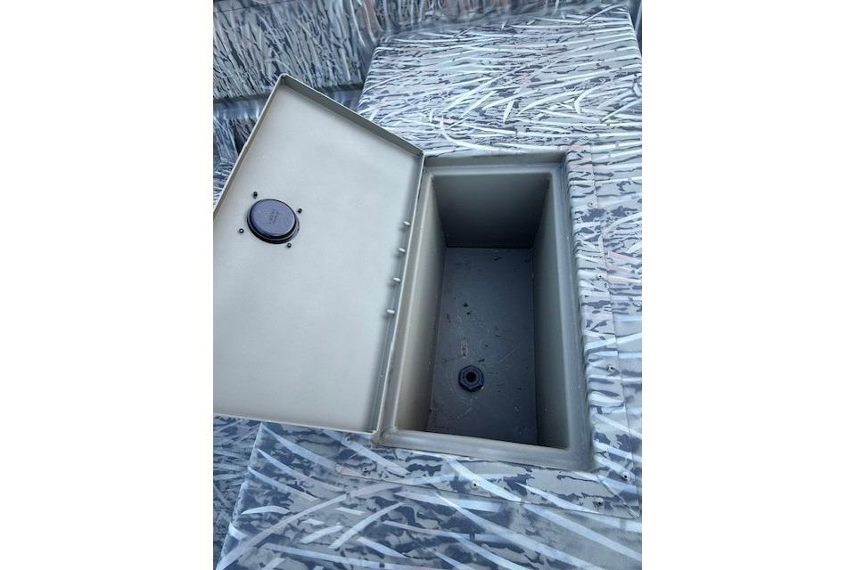 Open storage compartment in 2026 Tracker Grizzly 15 Jon boat, featuring camouflage design.