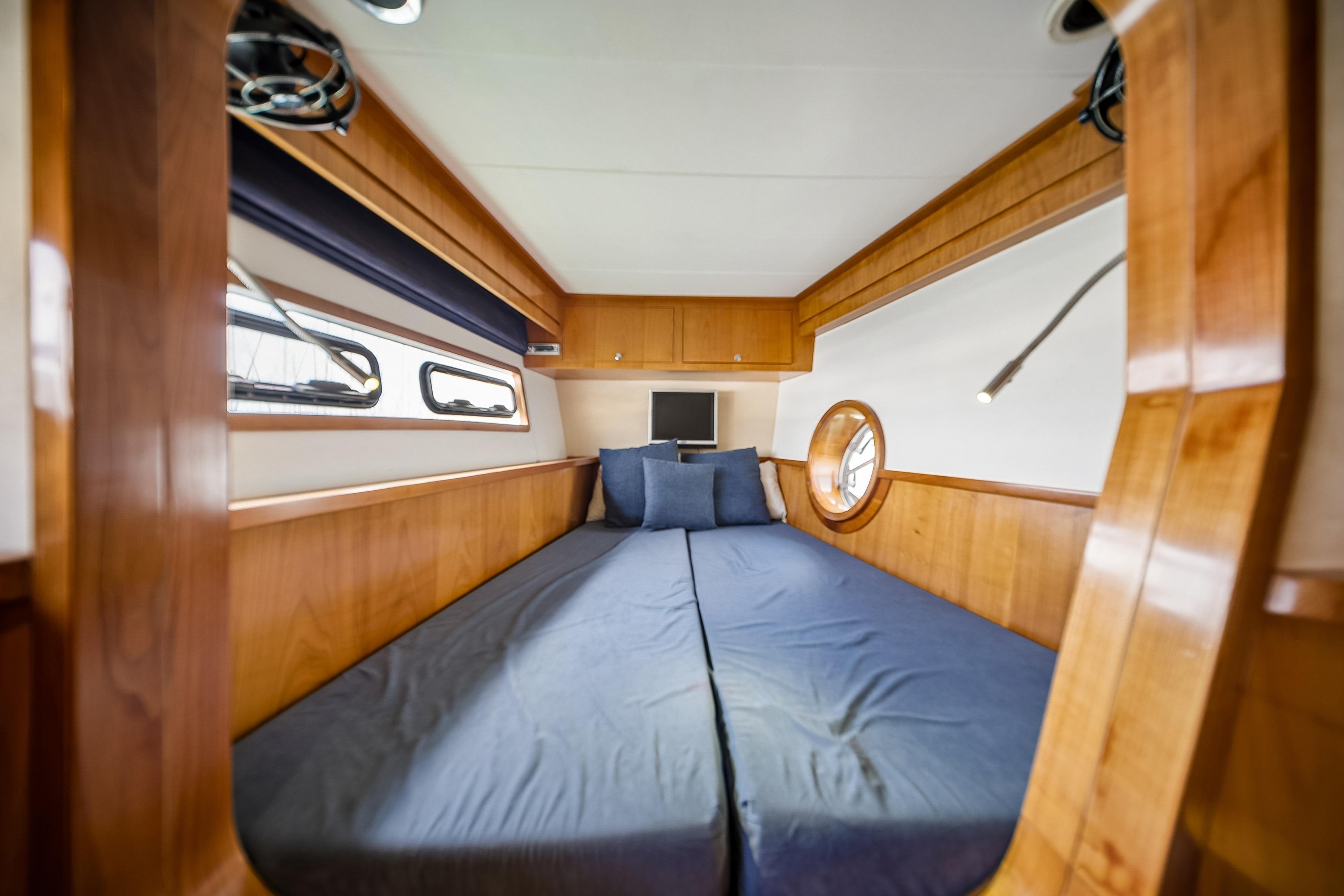 Luxurious wooden cabin interior of 2009 Catana 65 yacht with cozy bed and porthole.