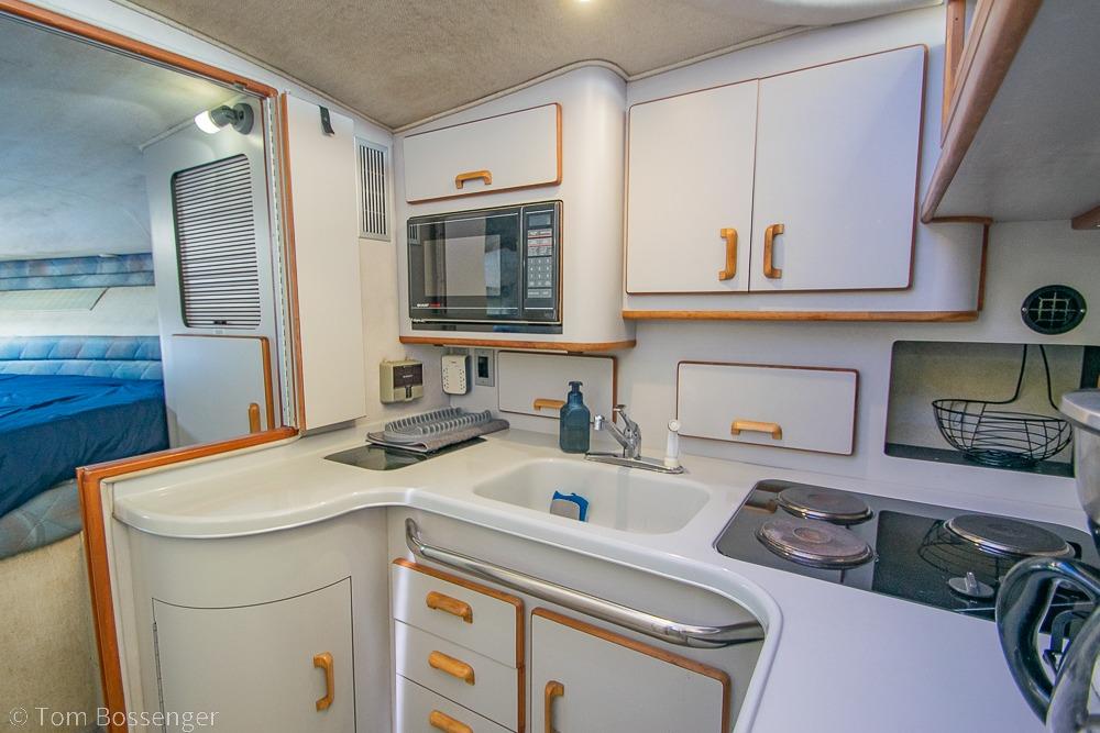 1991 Sea Ray 370 Sedan Bridge kitchen with white cabinetry and modern appliances.