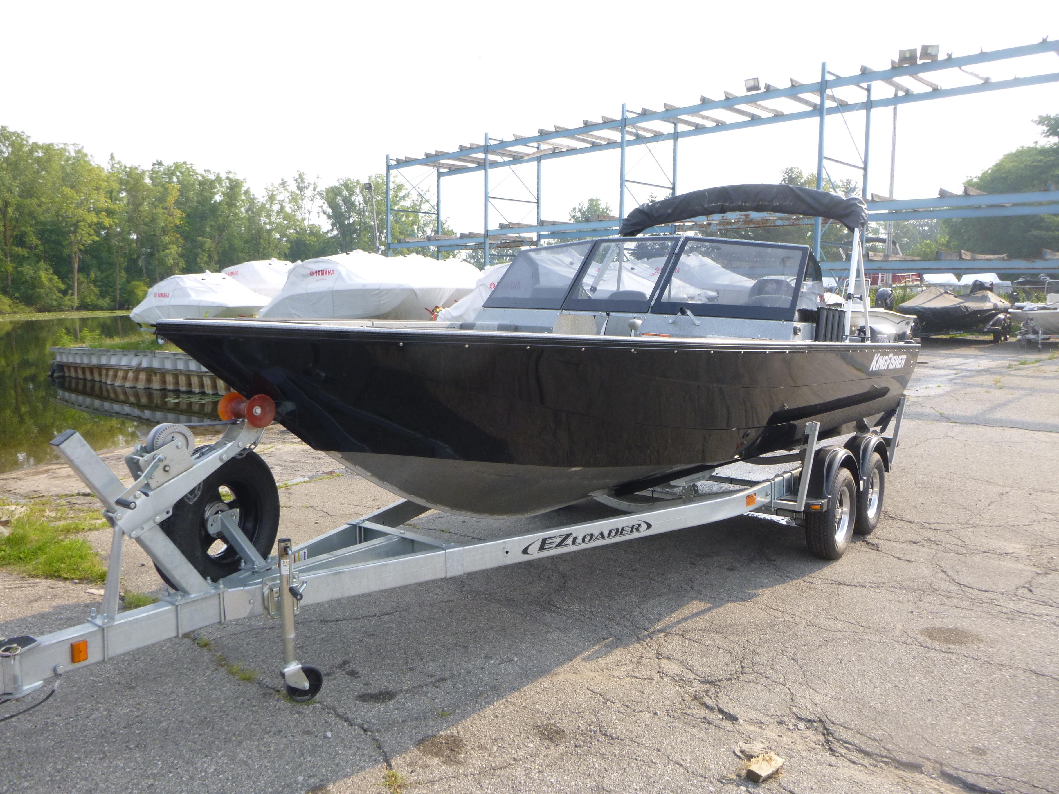 2025 KingFisher 2125 Arrow Sport boat on trailer, parked outdoors near water.