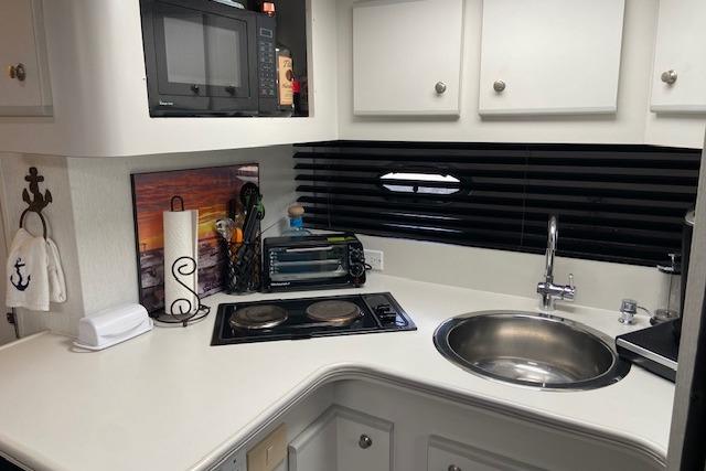 Compact kitchen area in a 1994 Cruisers Yachts 3675 Esprit with stove, sink, and microwave.