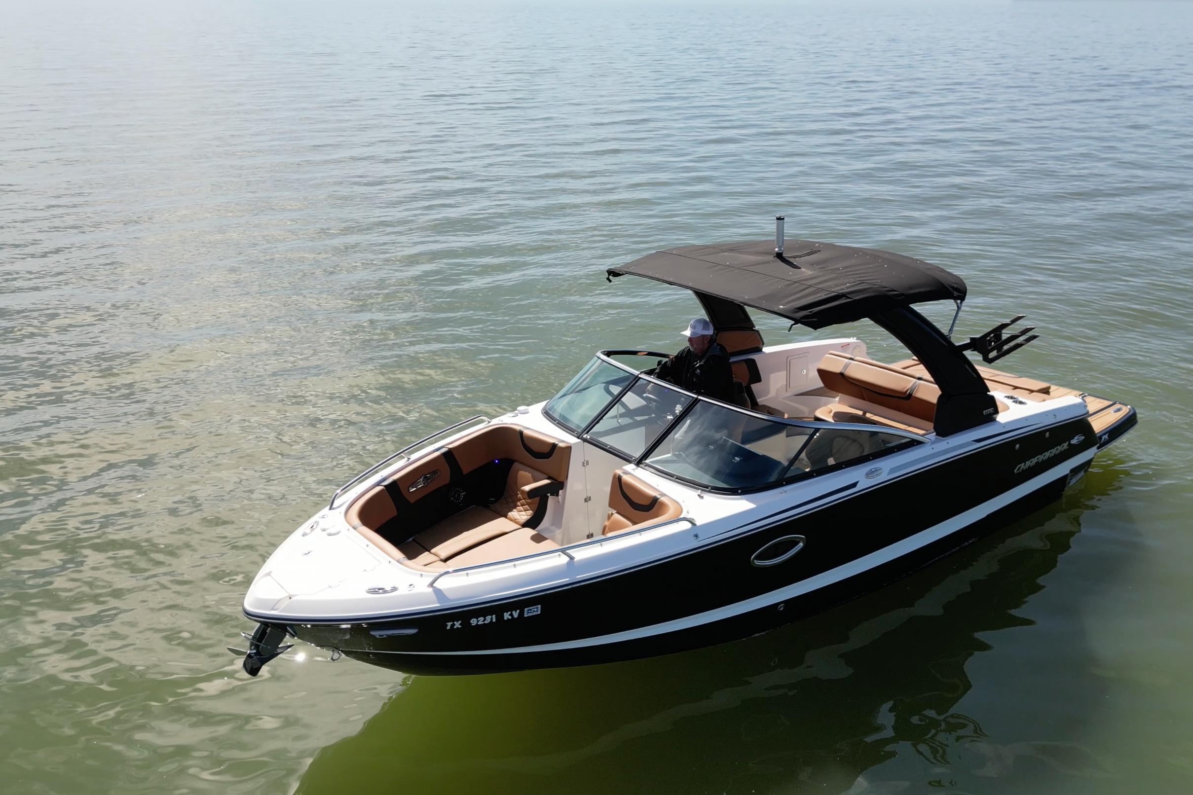 2023 Chaparral 26 Surf boat on calm water, featuring sleek design and spacious seating.