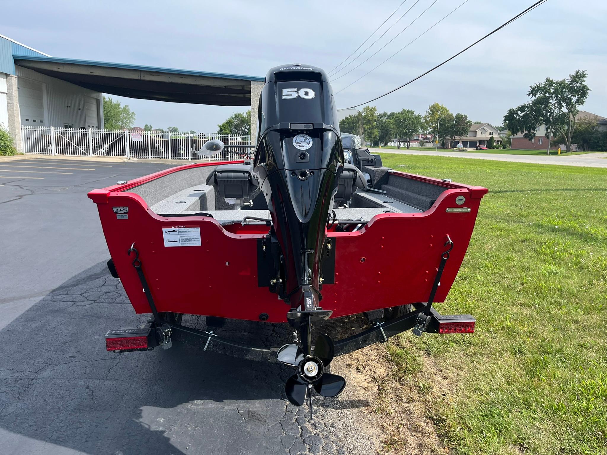 2026 Lund 1650 Angler SS boat with 50 HP motor, parked on grass.