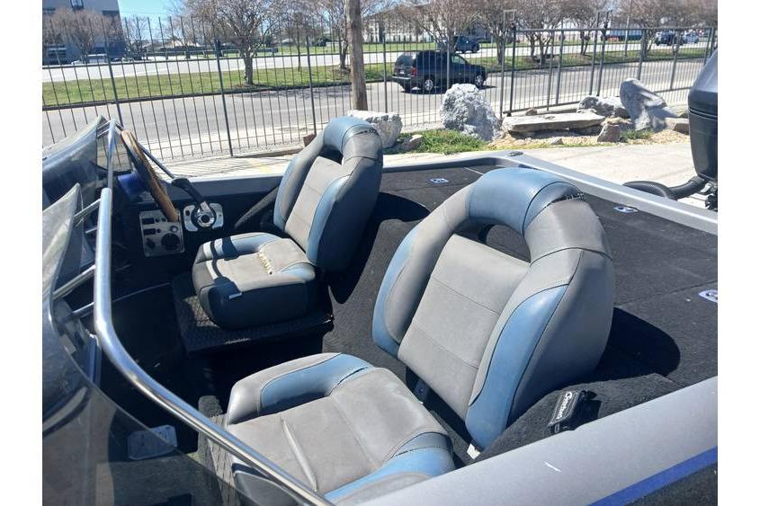 1994 Gambler 21 boat interior with two gray and blue seats, steering wheel, and dashboard.