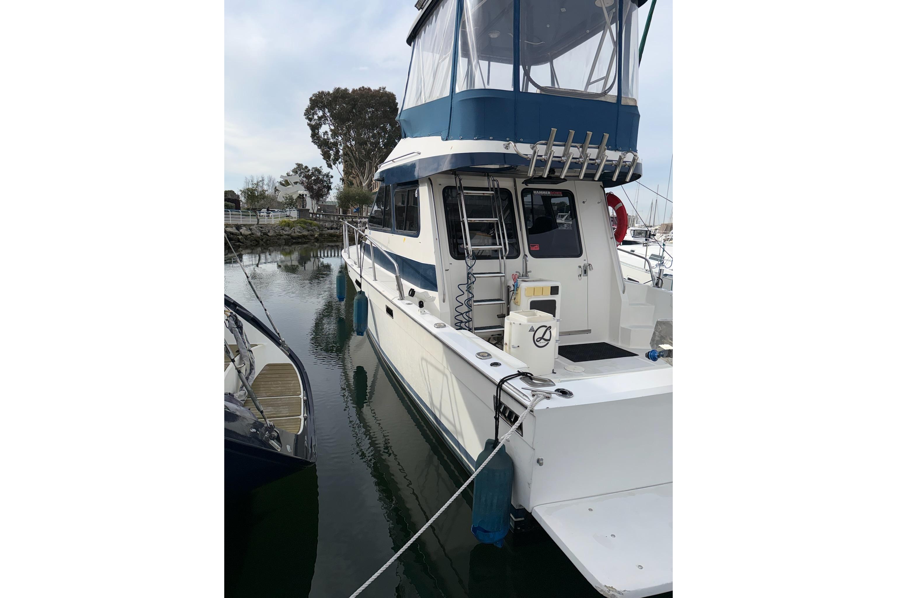 1990 Mediterranean Sport Fish boat docked in a marina, featuring a blue canopy.
