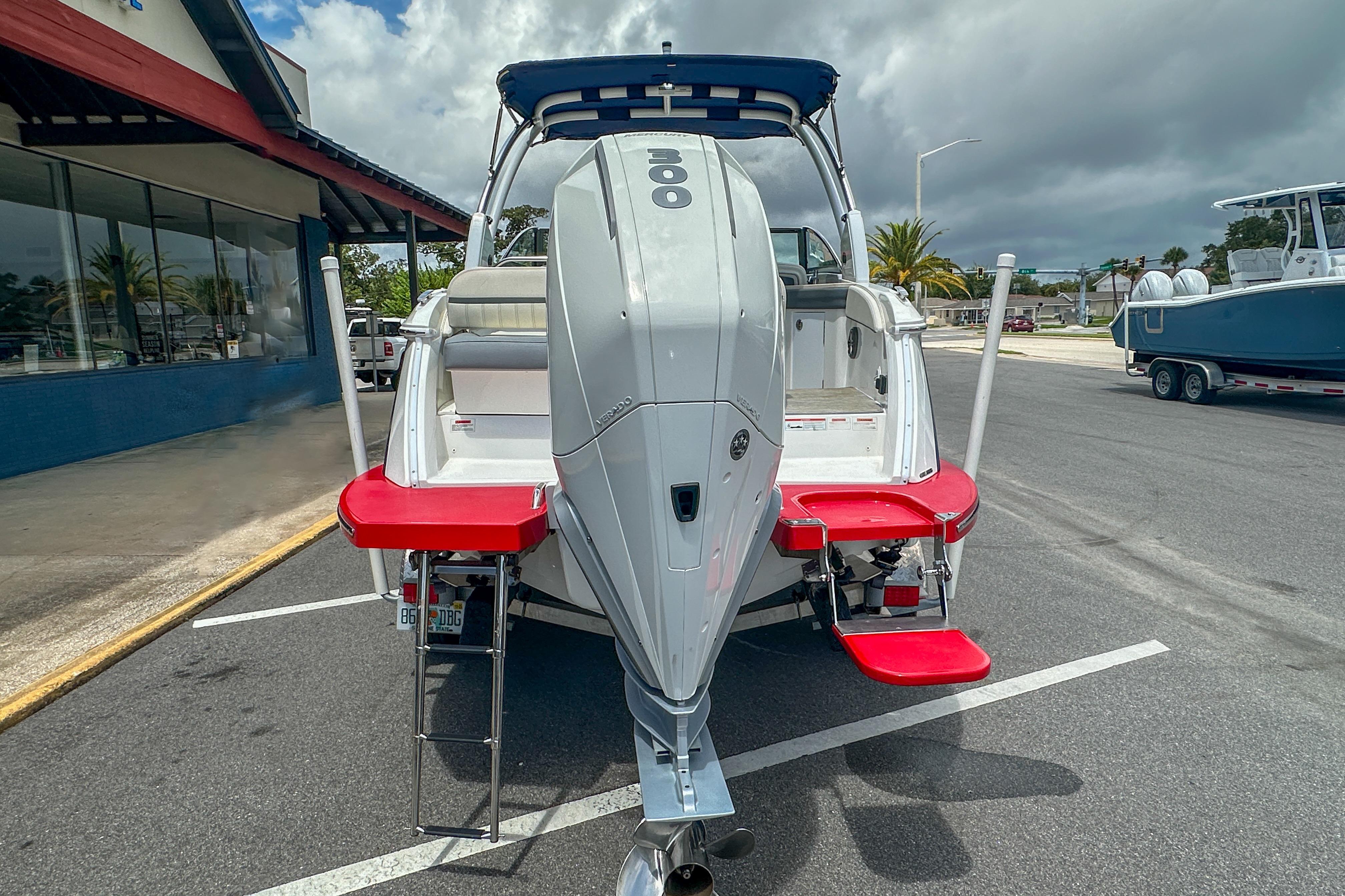 2022 Cobalt 25SC boat with outboard motor and red swim platform in parking lot.
