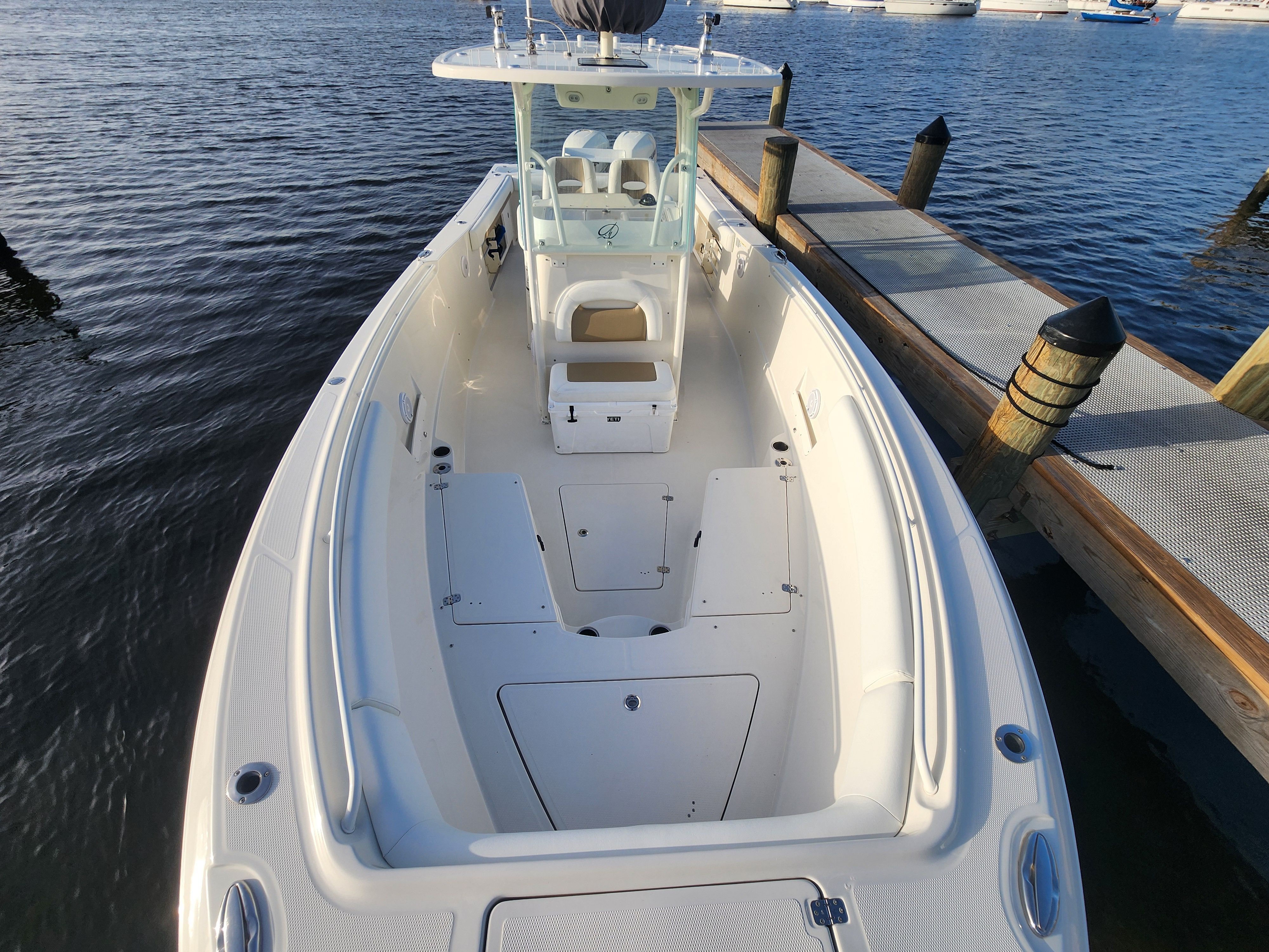 The 2017 Sailfish 320 CC is docked. It features a spacious deck and a central console.