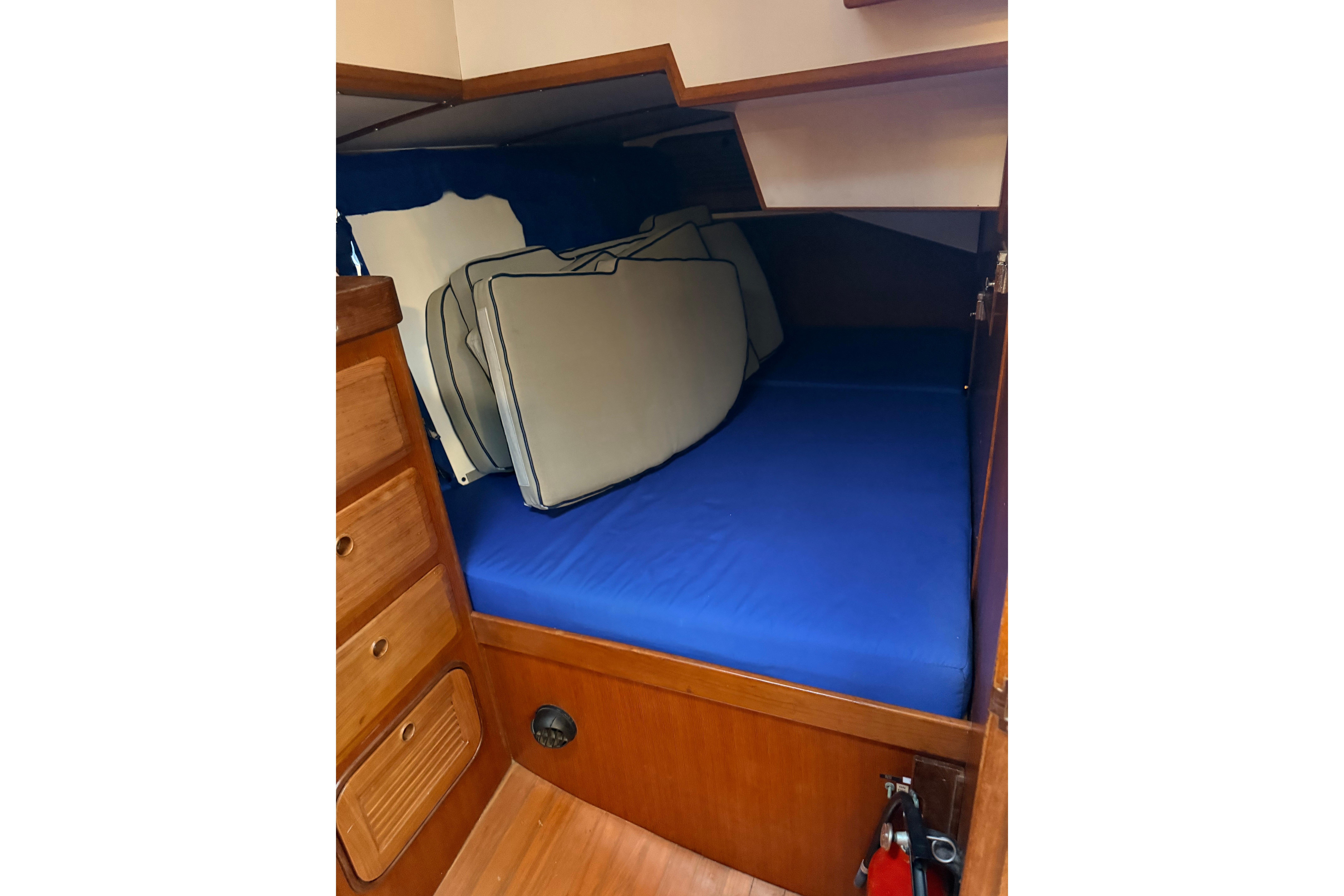 Cozy cabin interior of 1987 Norseman 400 sailboat with blue bedding and wooden storage.