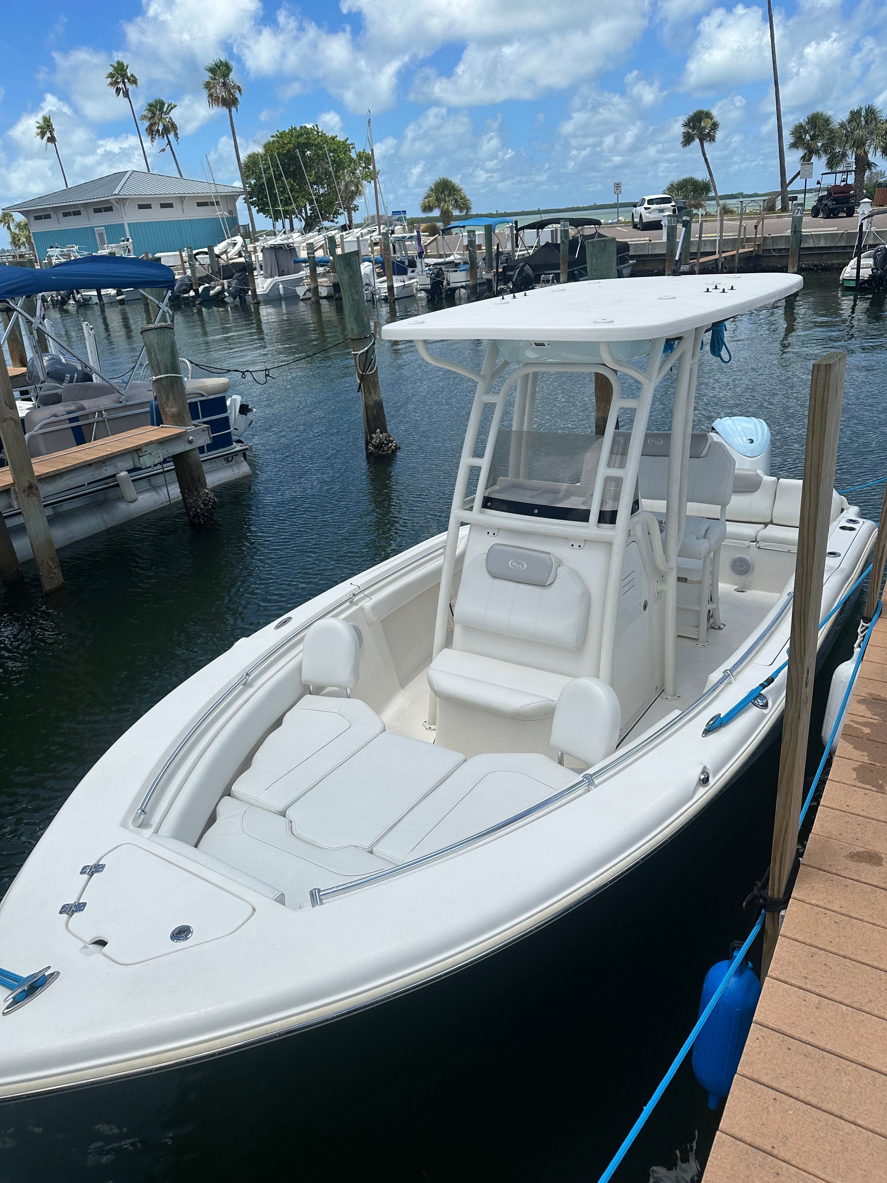 A white motorboat docked in a marina, surrounded by other boats.