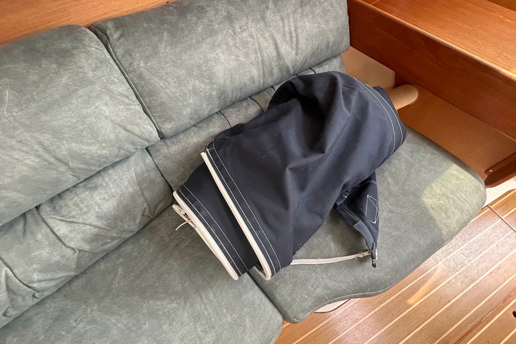 Folded sail on a green cushioned seat inside a 1998 Hunter 340 sailboat.