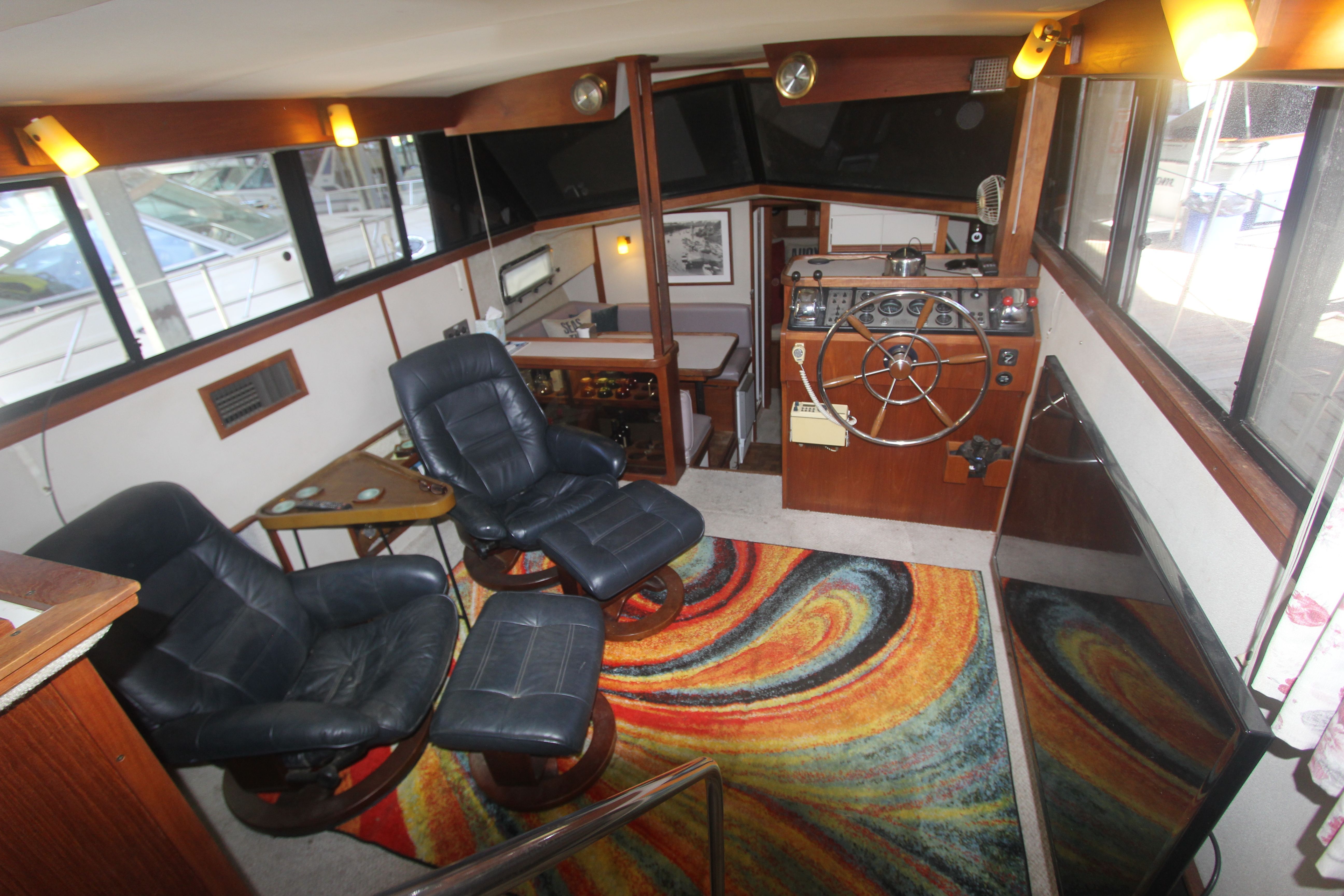 Interior of a 1988 Carver 3607 Aft Cabin Motor Yacht with leather chairs and colorful rug.