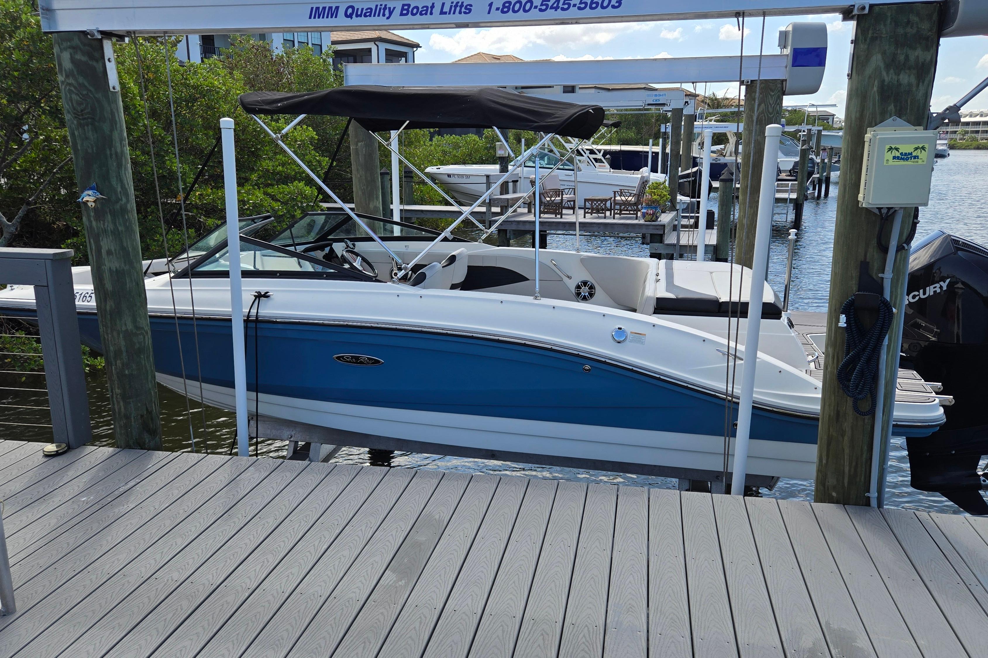 2023 Sea Ray SPX 210 boat docked on a lift, featuring a sleek blue and white design.