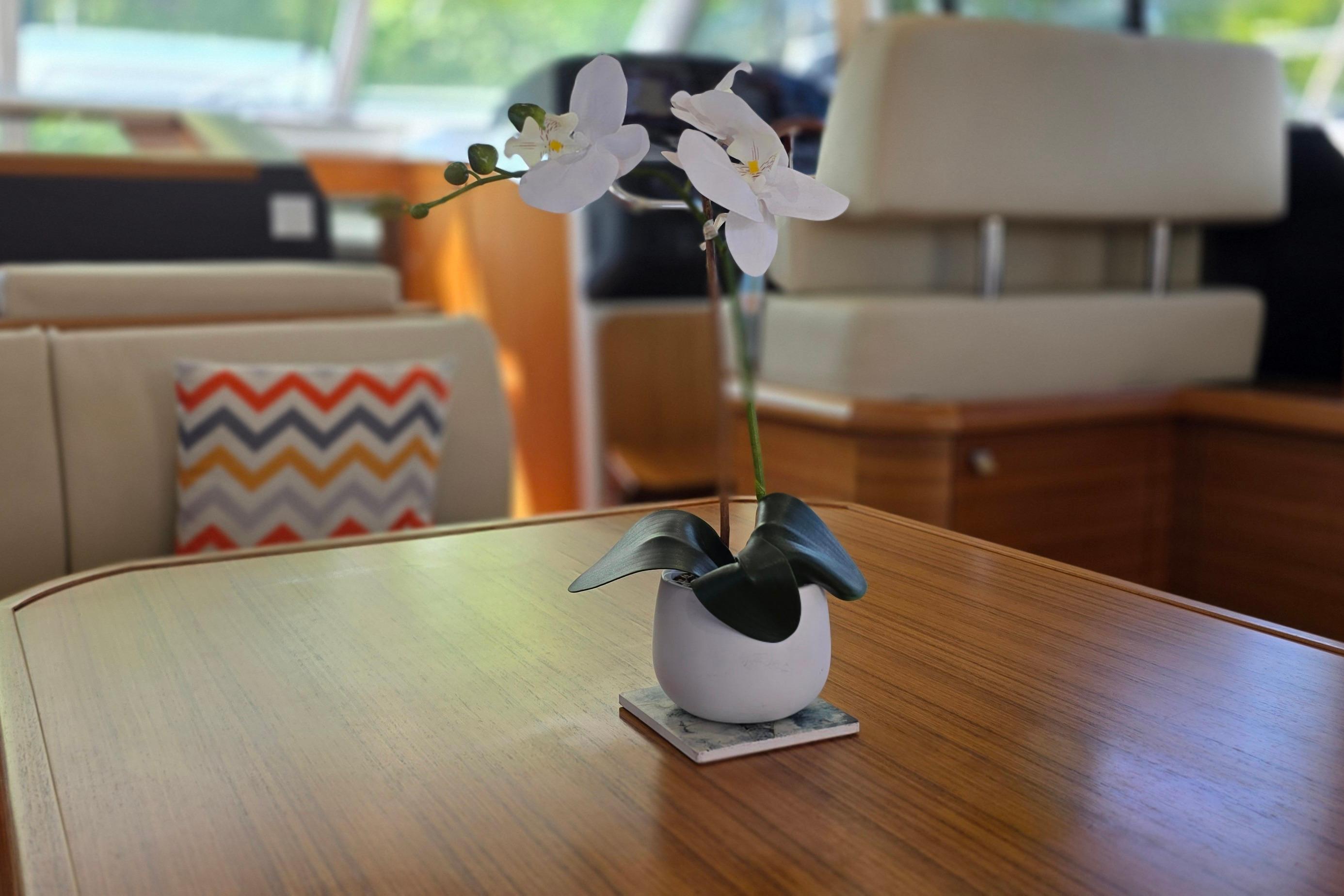 Elegant interior of 2023 Greenline 40 yacht with orchid centerpiece on wooden table.