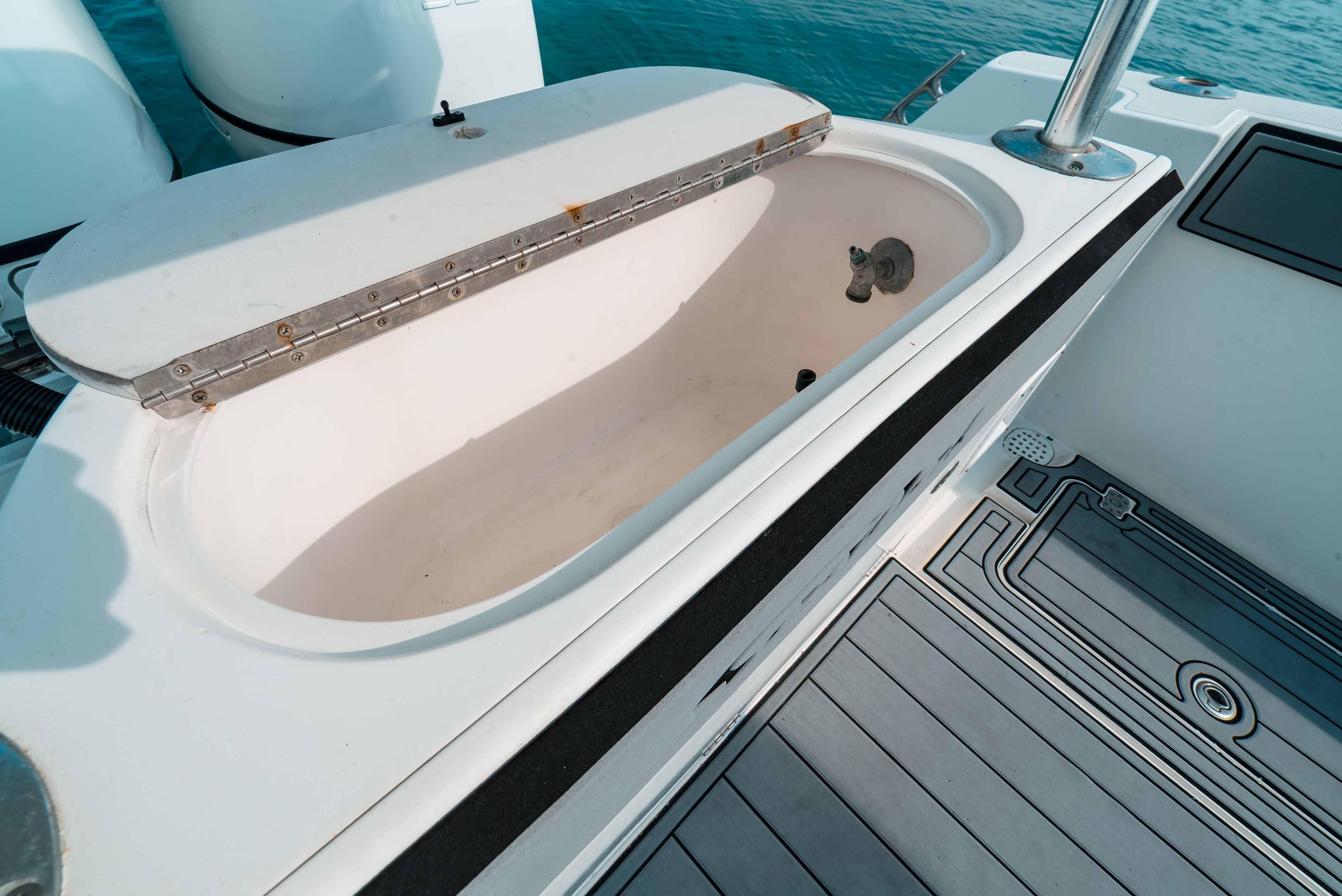 An open storage compartment on a boat with gray deck flooring.