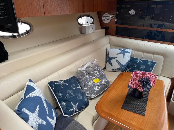 2003 Tiara Yachts 3500 Open interior with starfish-themed cushions and wooden table.