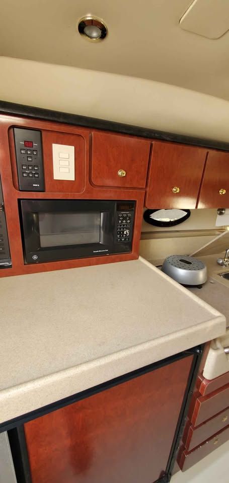 The 2002 Wellcraft 3300 Martinique's galley features a microwave and wooden cabinets.