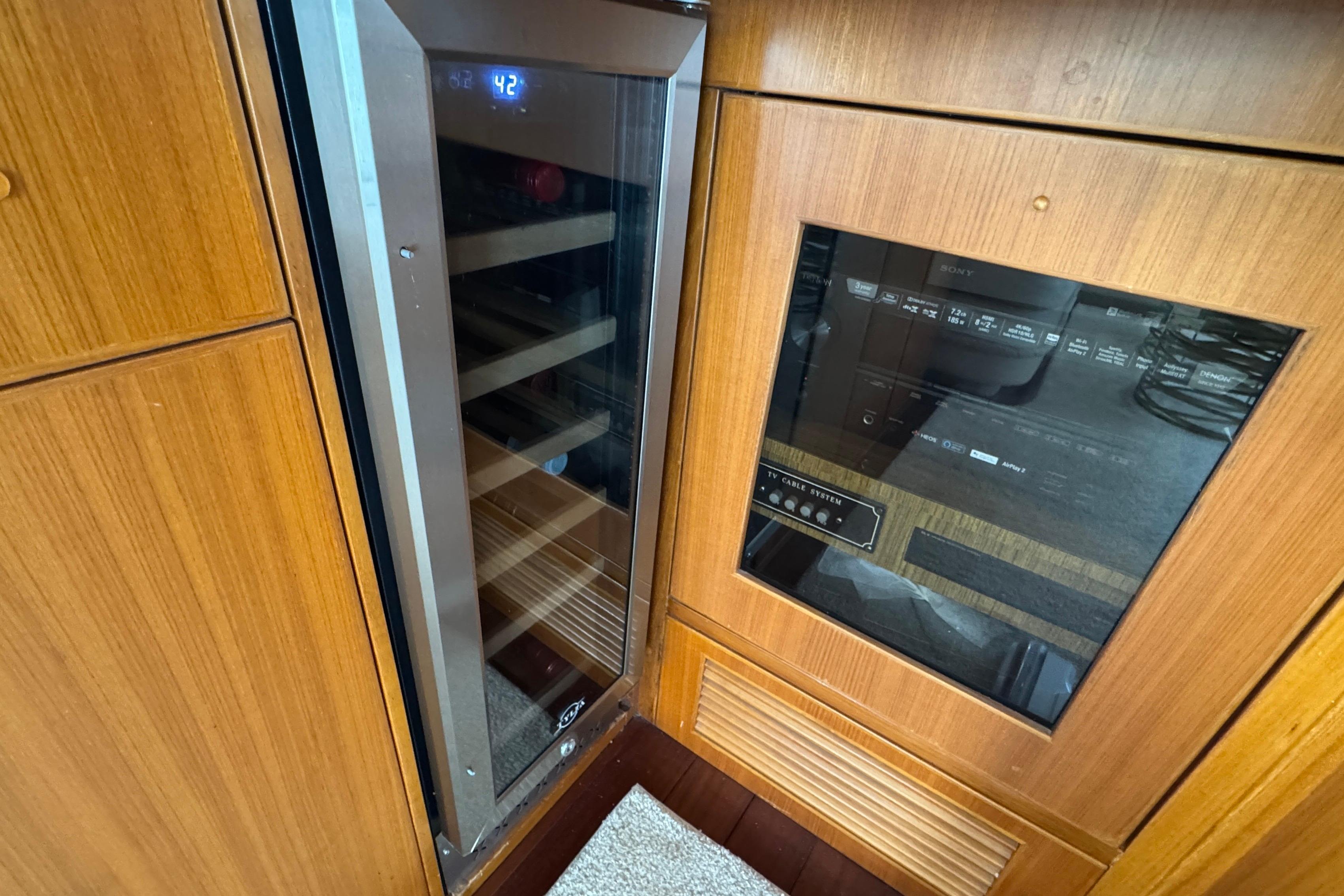 Wood-paneled interior of 2007 Jefferson Pilothouse 52 SE with wine cooler and control panel.
