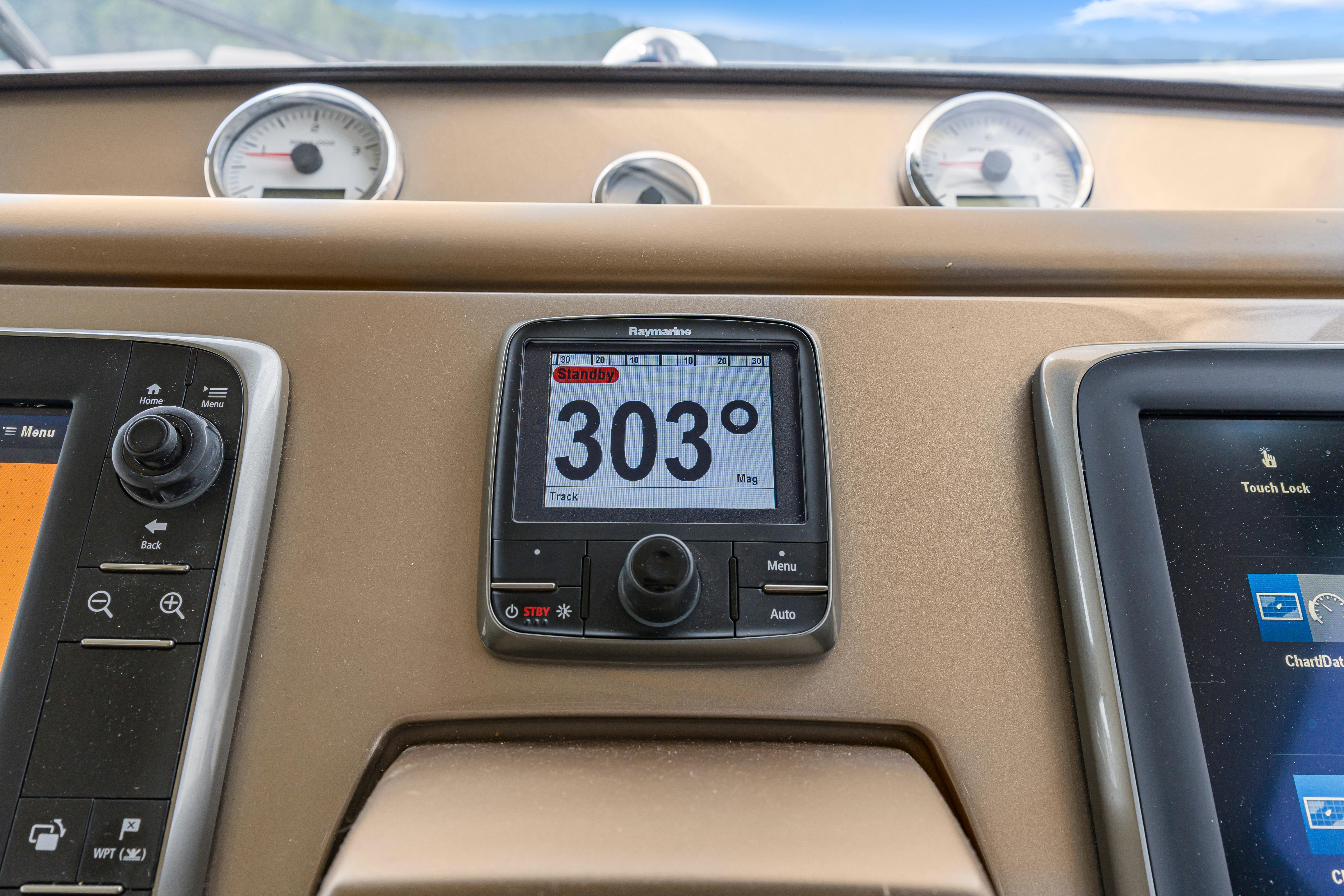 Boat dashboard with navigation instruments, featuring a Raymarine display showing 303 degrees. Prestige 500, 2017.