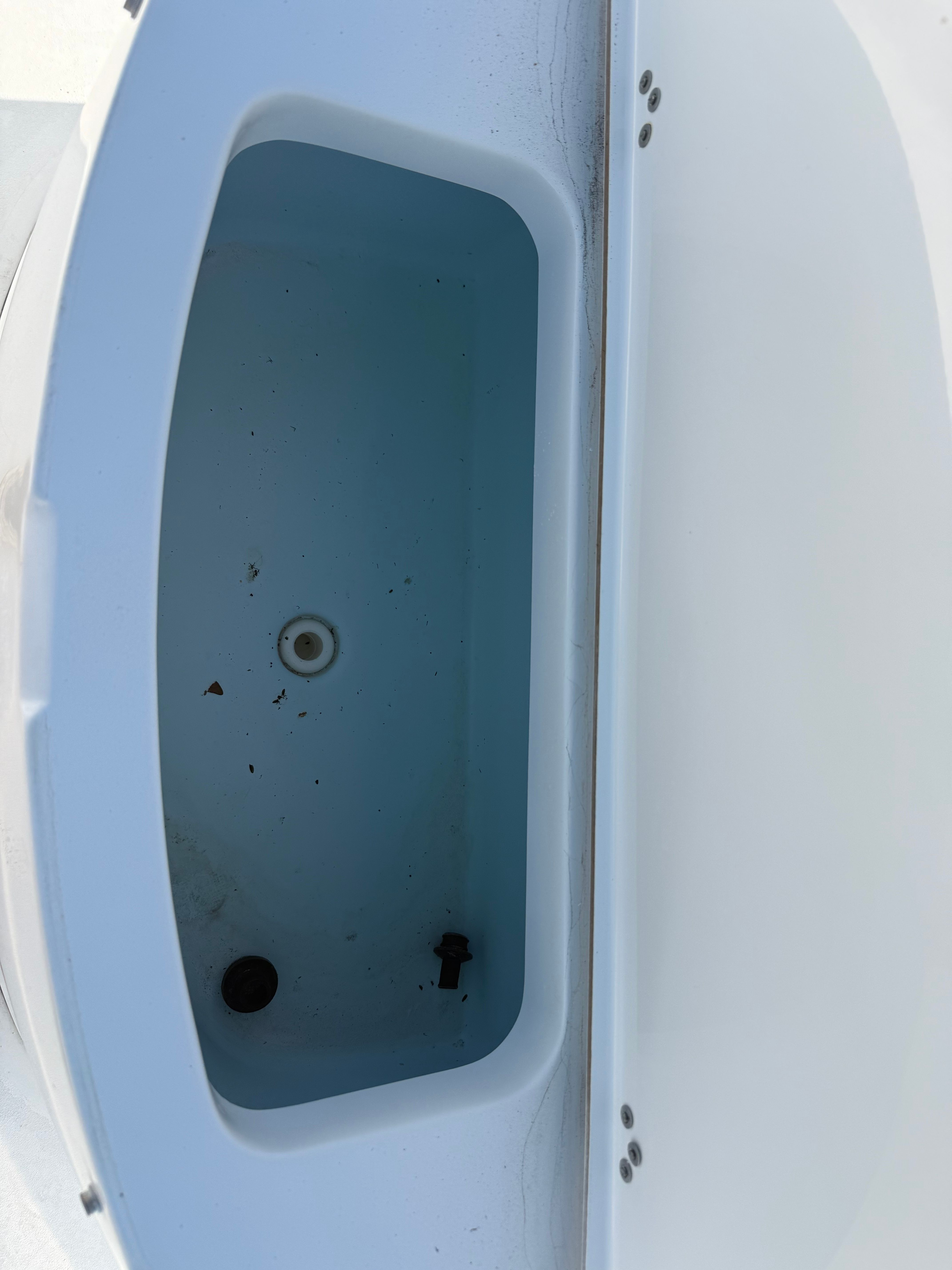 An empty, rectangular storage compartment on a boat with a white rim and blue interior.