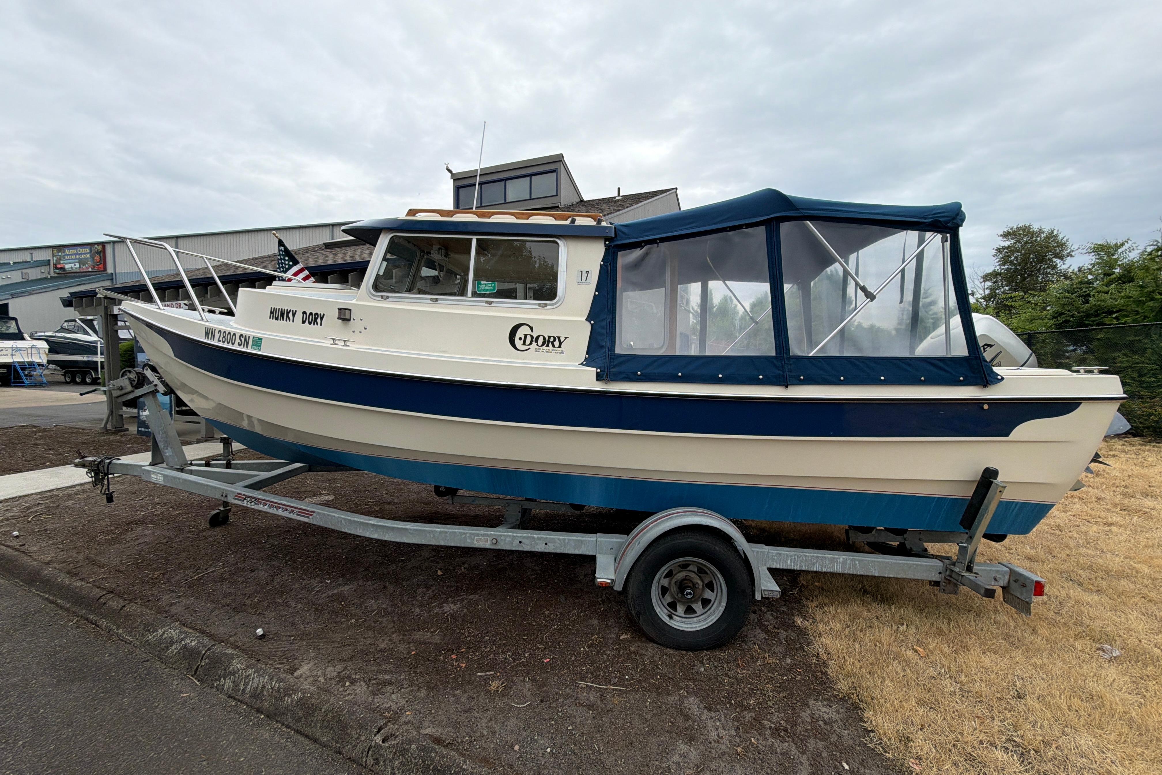 1989 C-Dory 22' Angler boat on trailer, blue and white, parked outdoors.