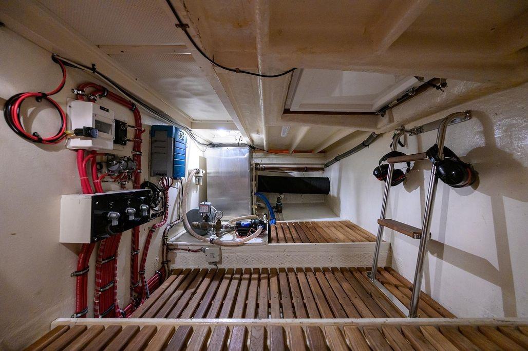 Engine room of 1999 Grand Banks 42 Europa yacht with wooden flooring and mechanical equipment.