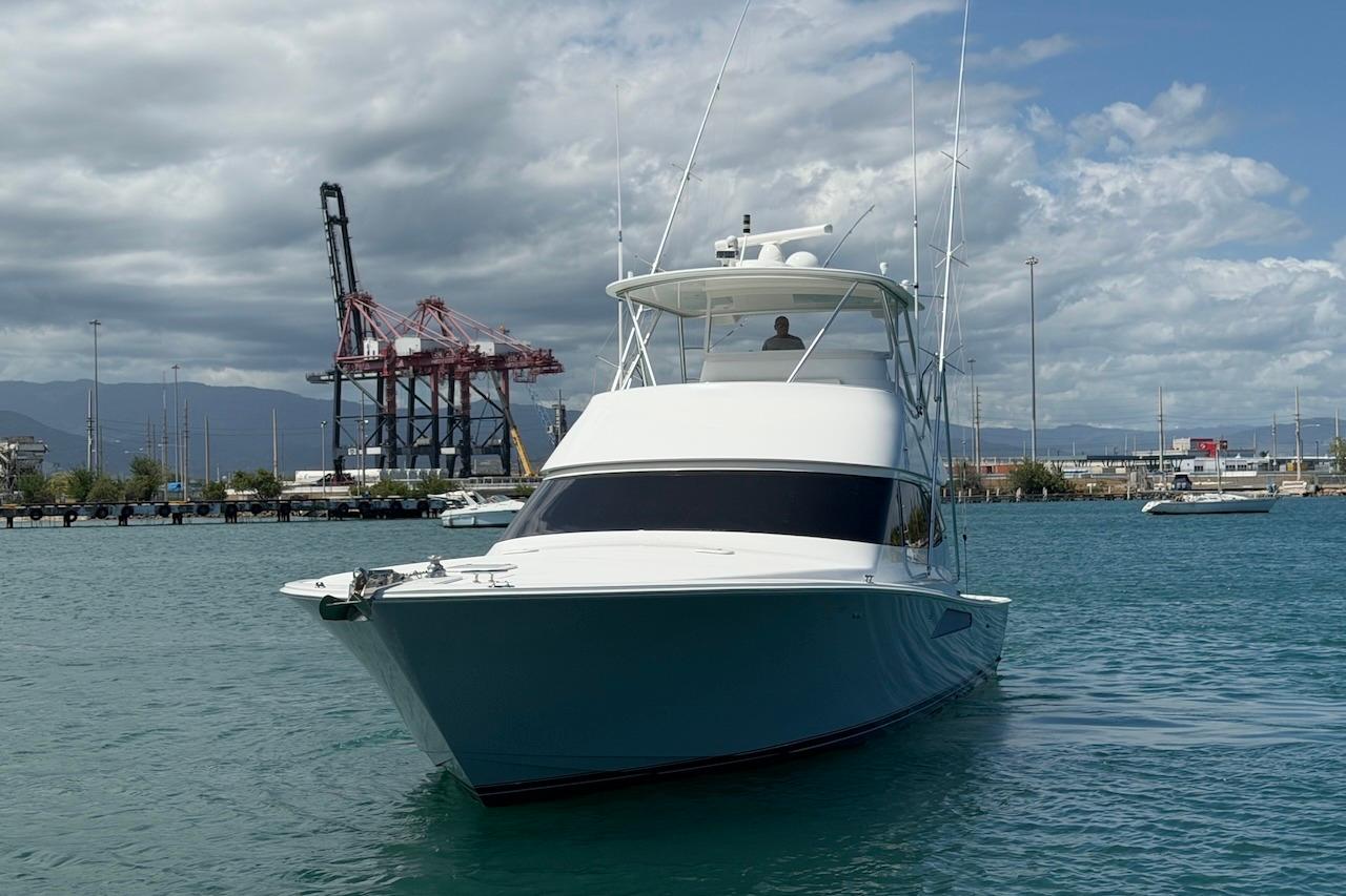 2012 Viking 50 Convertible yacht docked in a harbor with cranes in the background.