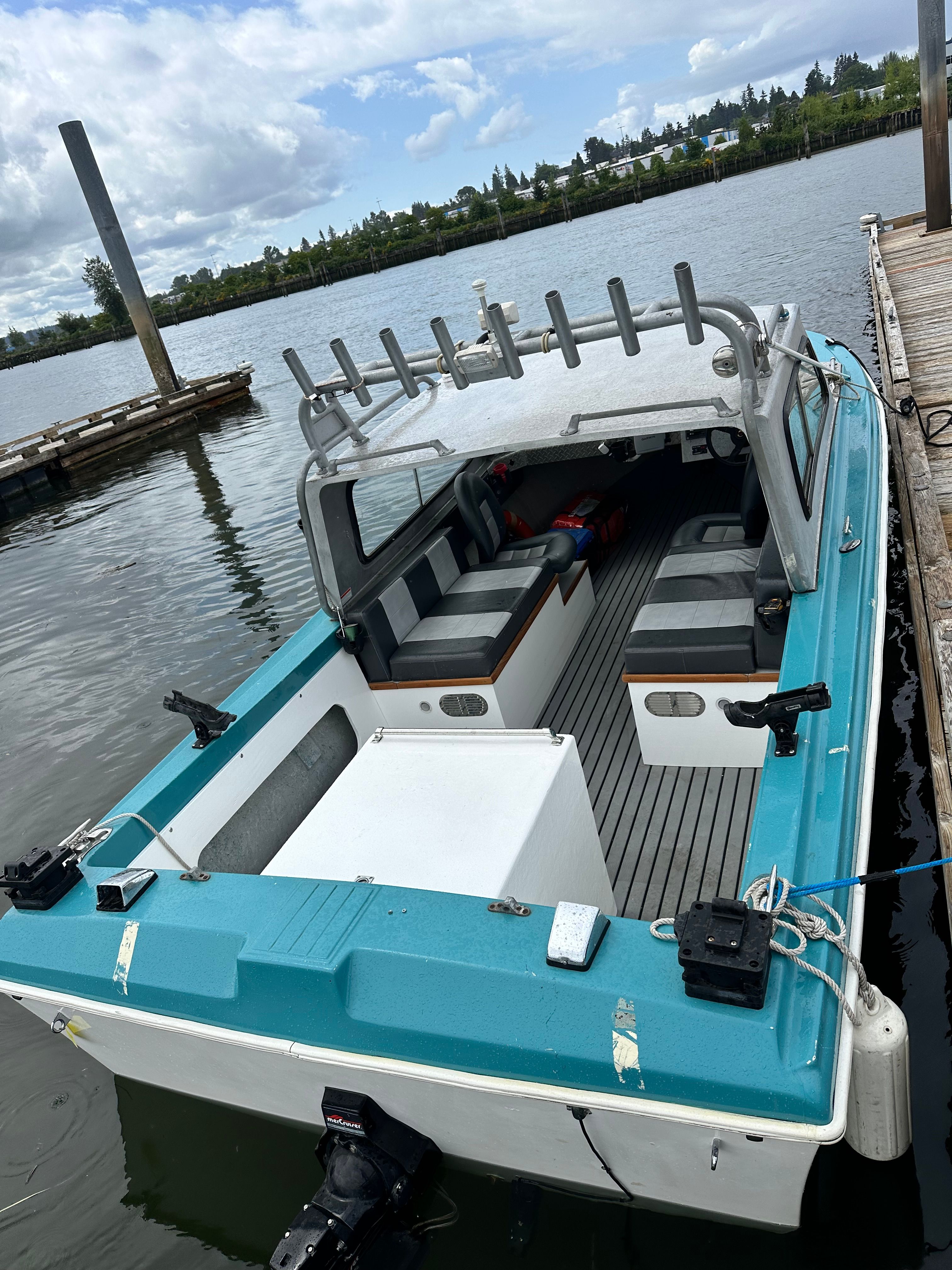 A restored 1967 Fiberform boat docked. It features a turquoise exterior and an open cabin.
