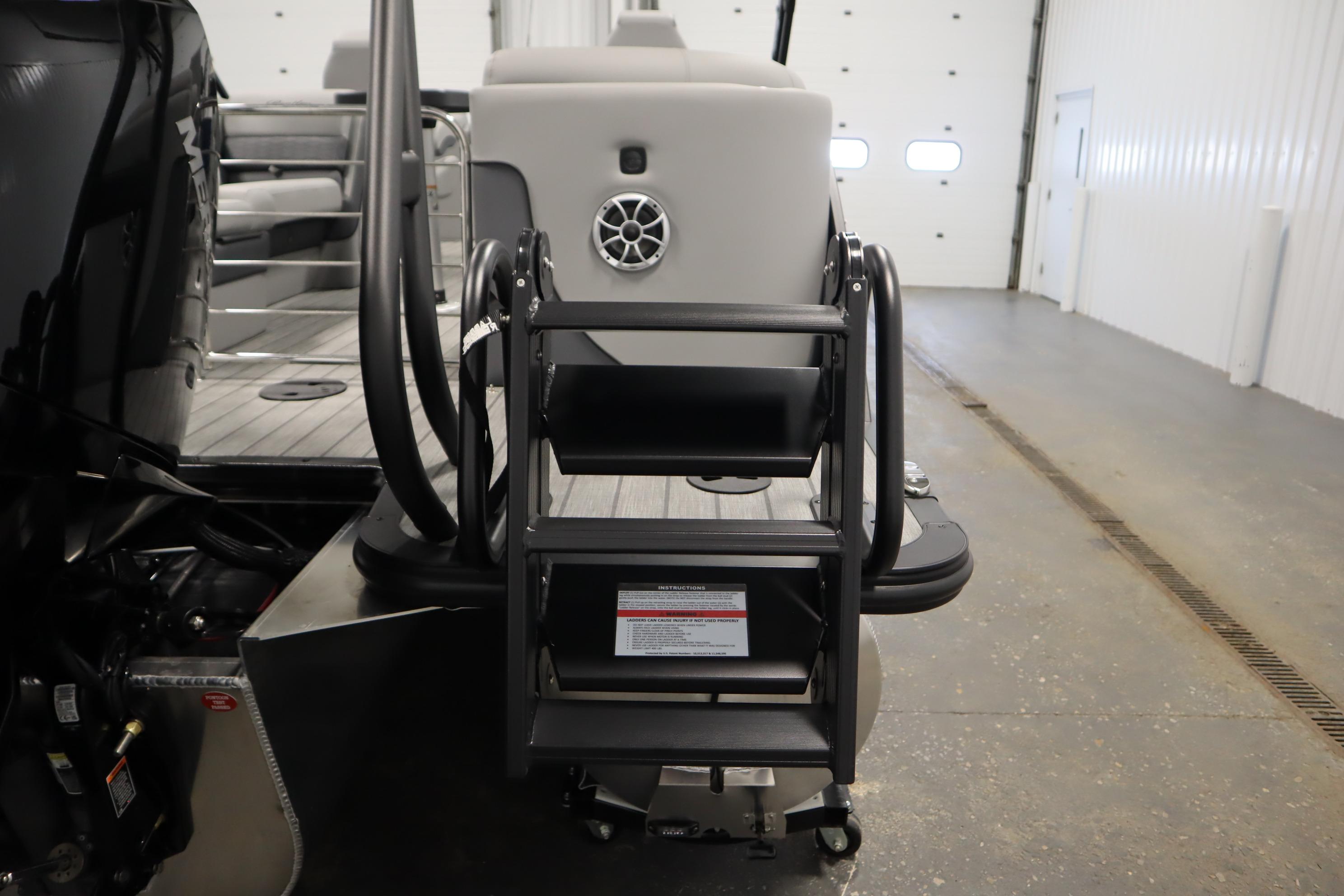 2025 Bentley Pontoons Elite 253 Admiral Tri-toon rear view with boarding ladder in a garage.